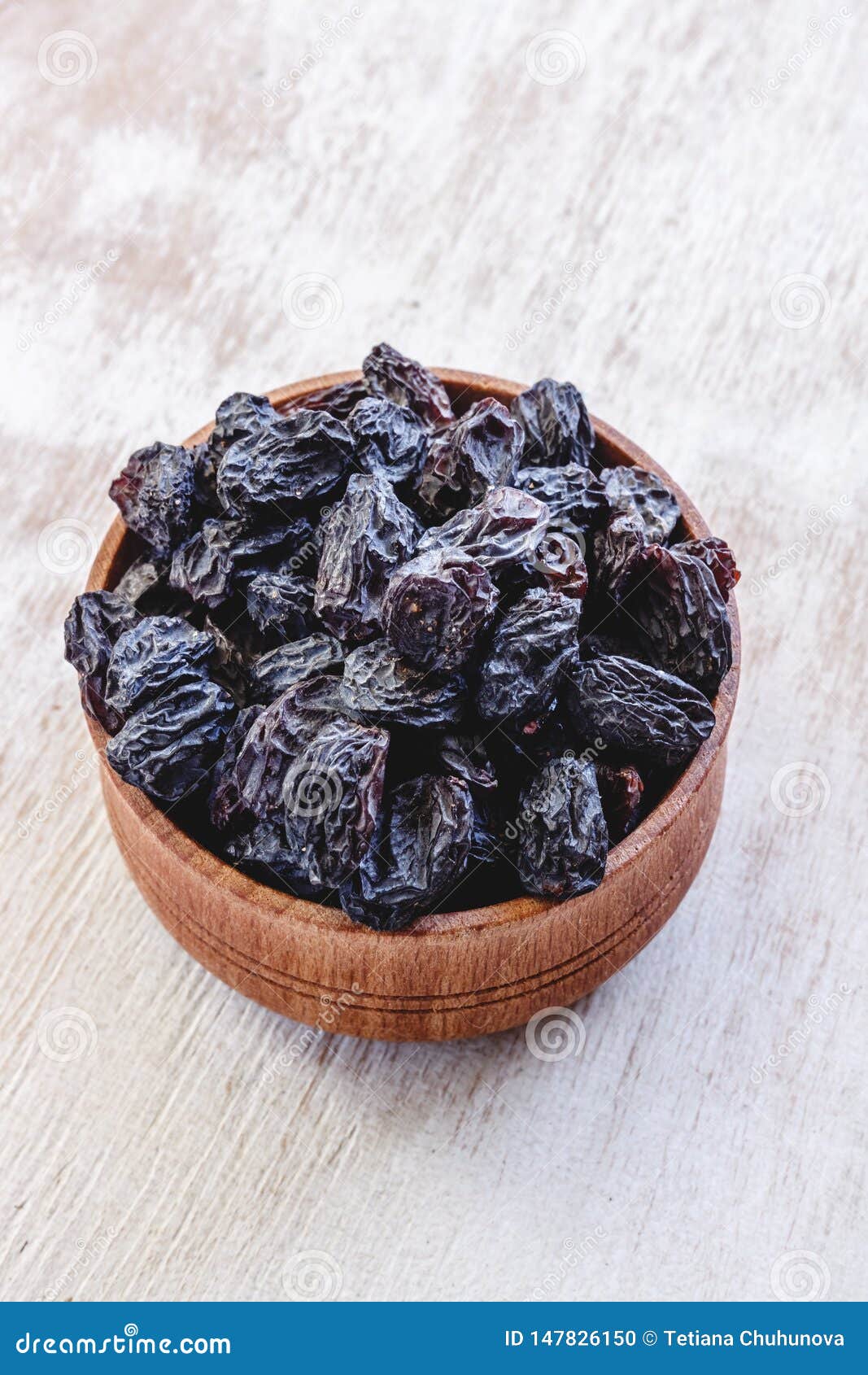 Dark Blue Raisins in a Wooden Bowl on a Bright White Background. Close ...