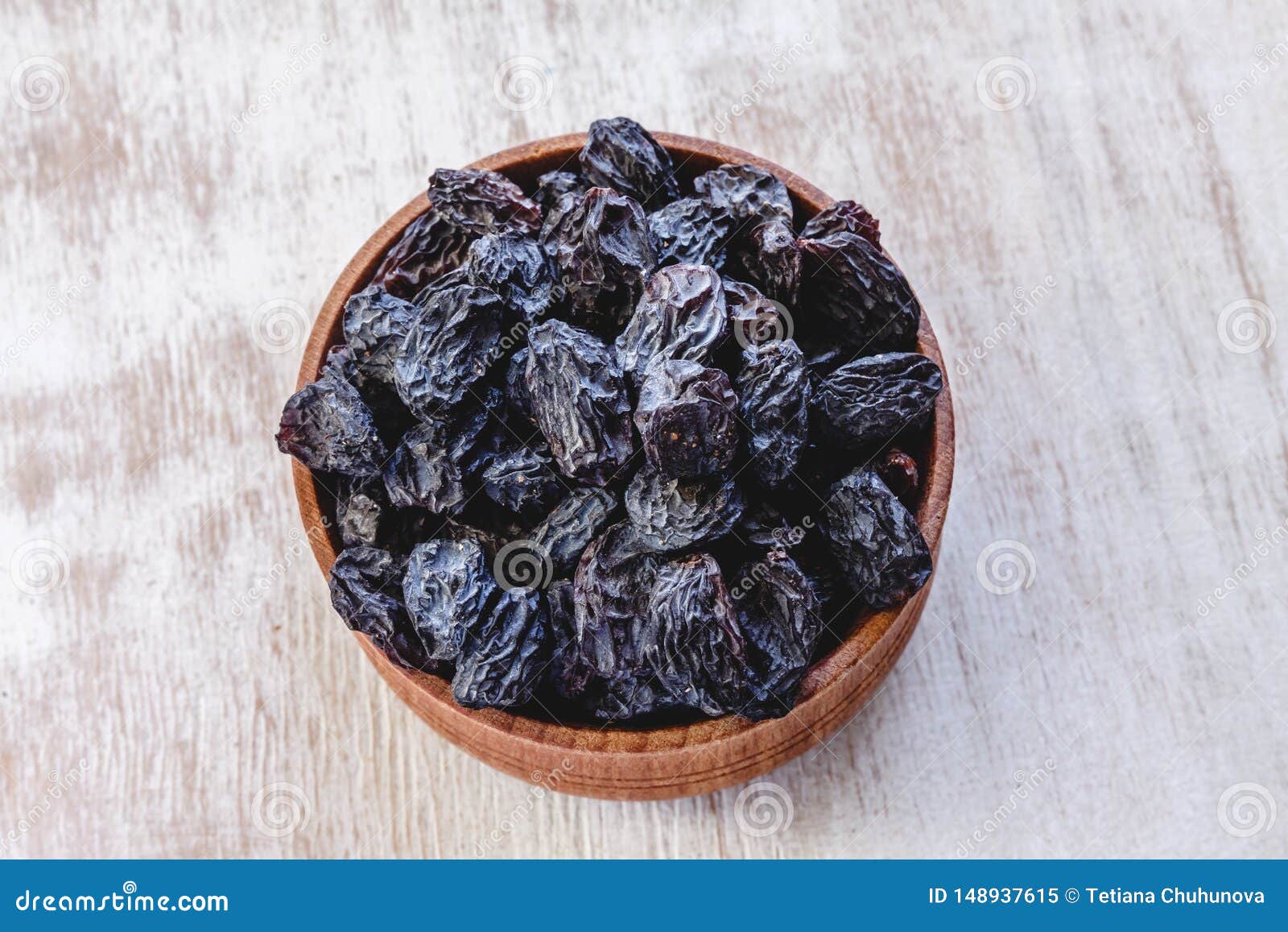 Dark Blue Raisins in a Wooden Bowl on a Bright White Background. Close ...