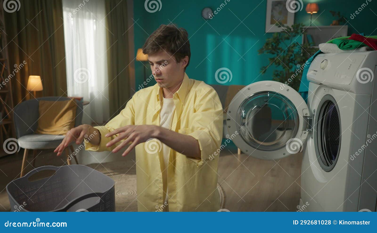 Darkhaired Man Standing Next To a Washing Machine, Unloading it. the