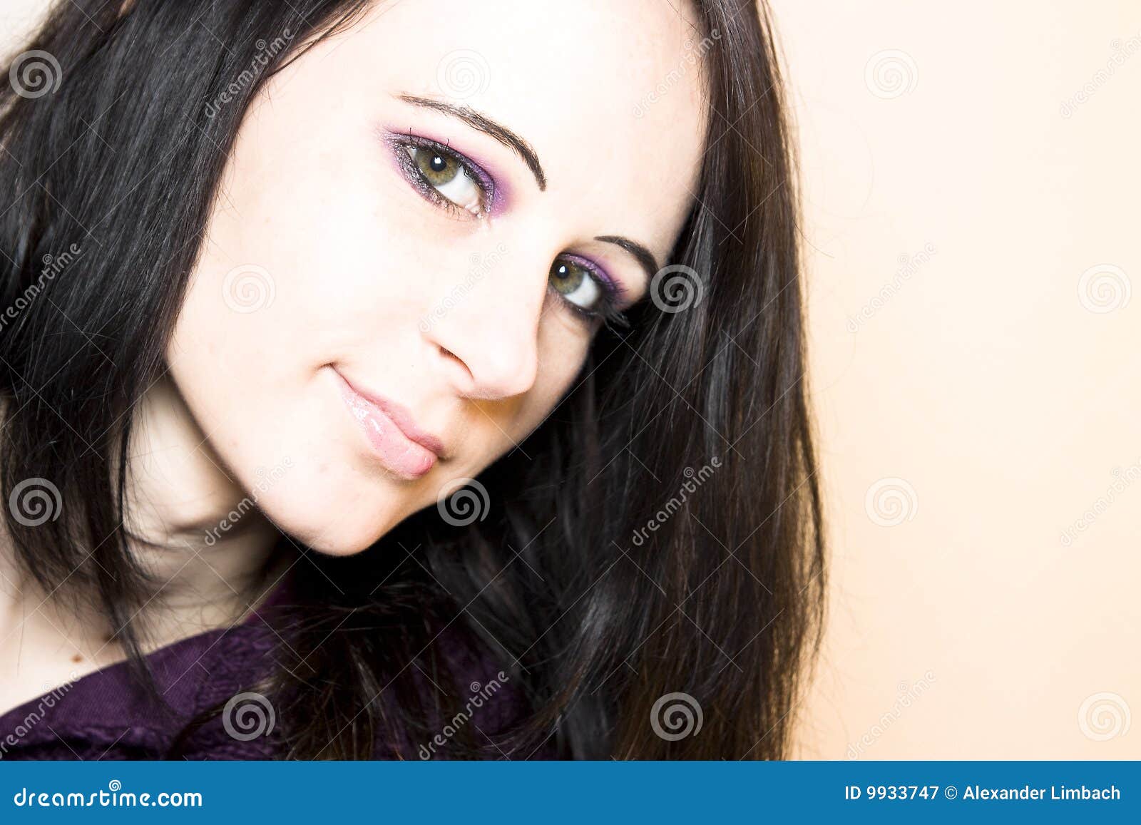 Dark haired woman. Horizontal studio portrait closeup of an attractive dark-haired young woman against a tan background.