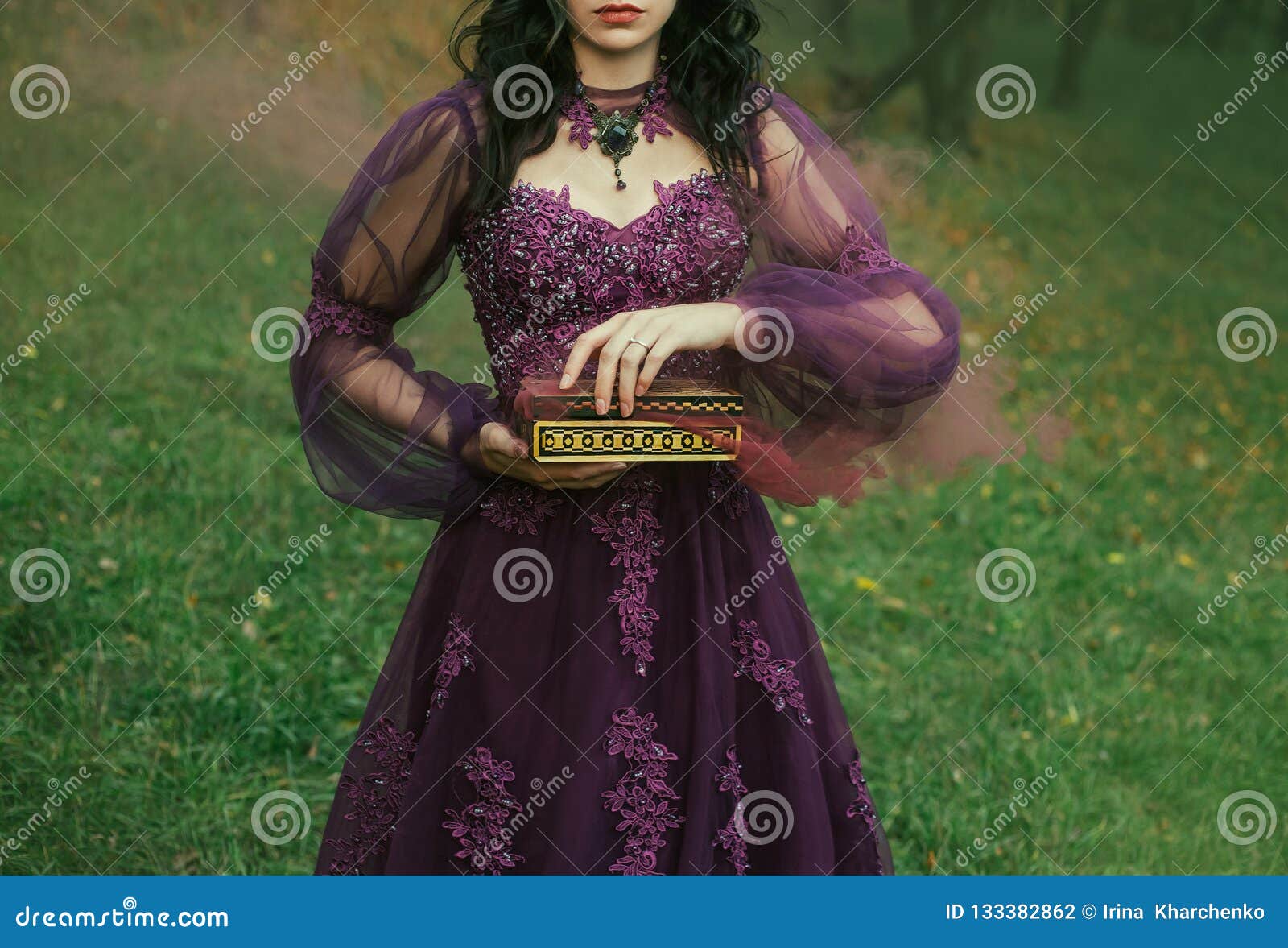 a dark-haired young lady holds in her hands an open pandora`s box, the red maroon thick fog of evil and disease slowly