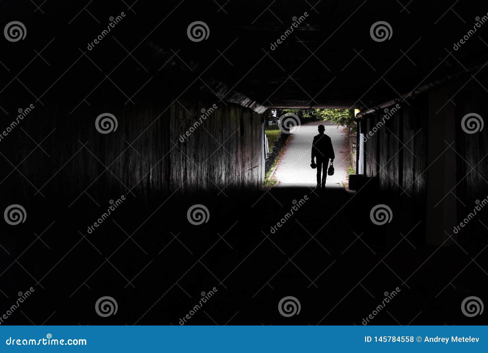 In A Dark Tunnel Silhouette Of A Walking Man, The Background Of Trees ... Silhouette Man Walking Tunnel