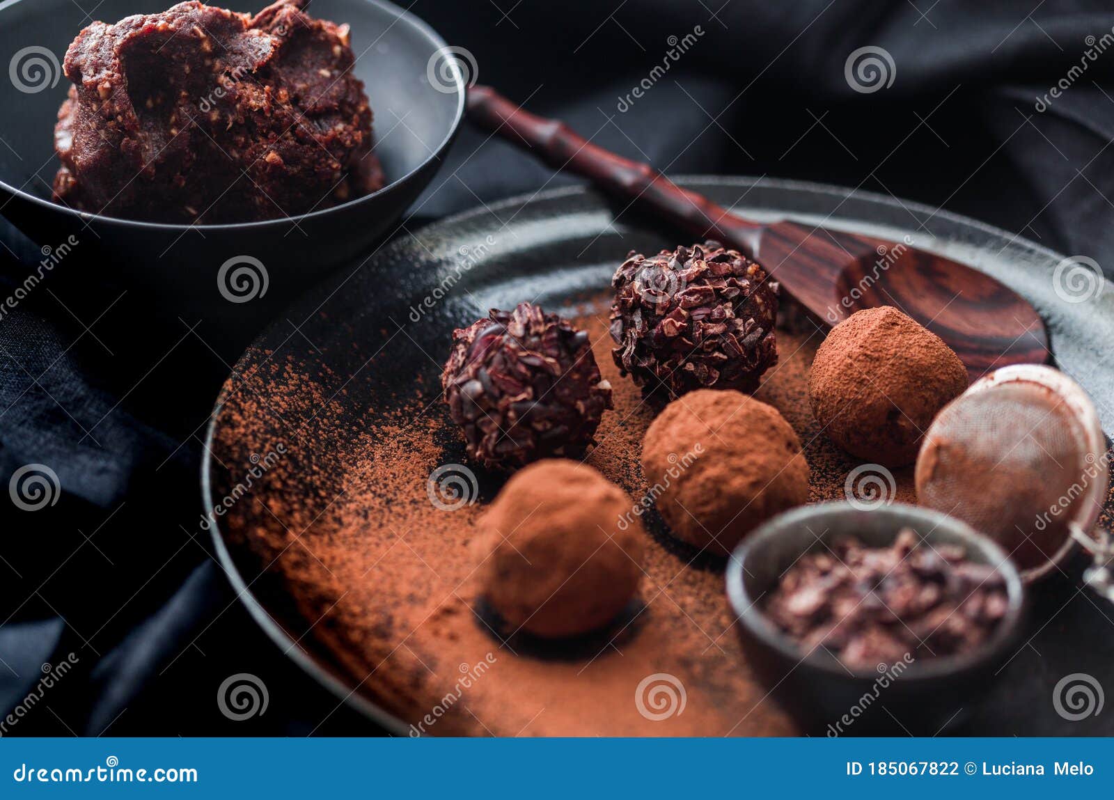 Date Energy Ball with Cocoa on a Black Dish and Cocoa Nibs Stock Photo