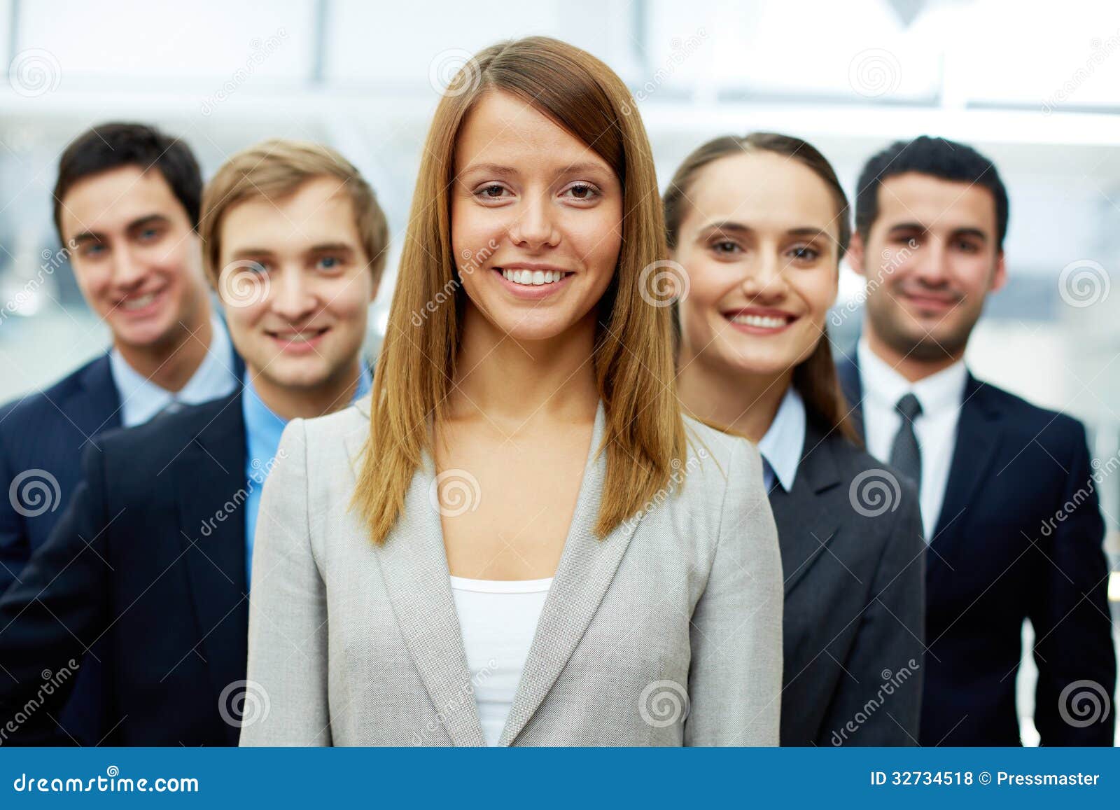 Datore di lavoro grazioso. Donna di affari felice che esamina macchina fotografica con i soci astuti dietro