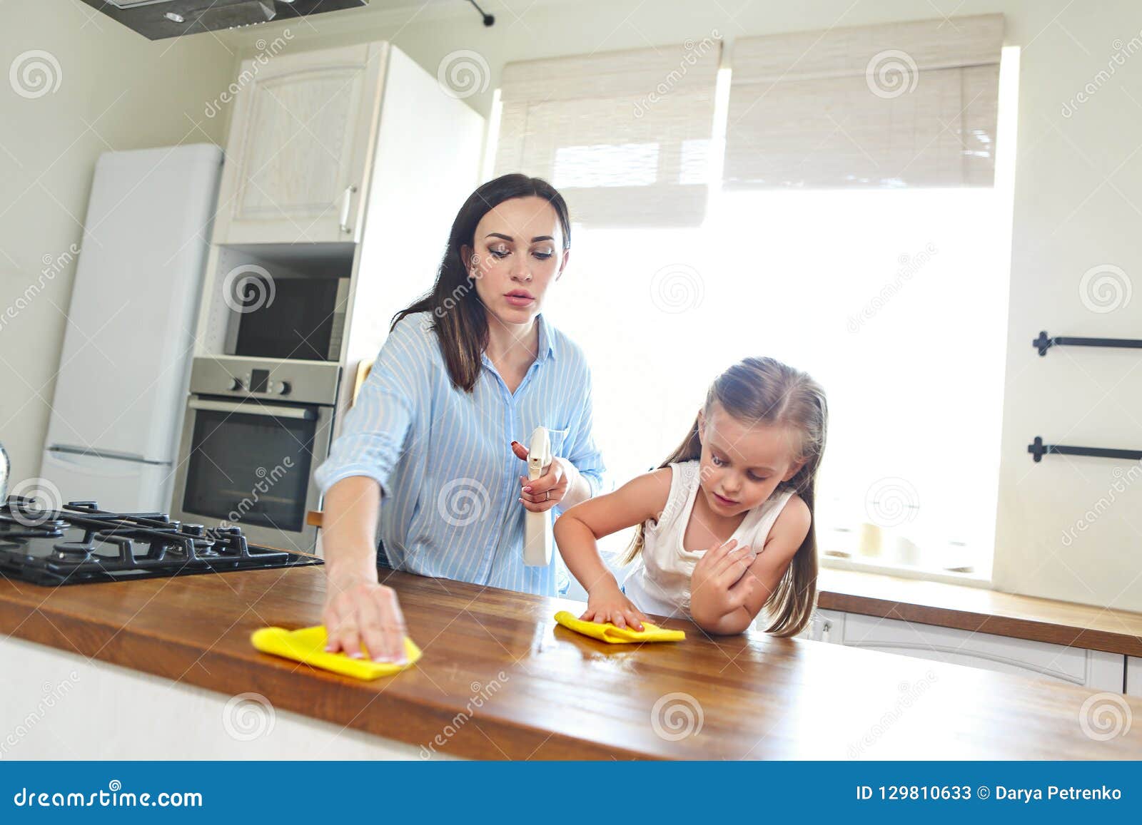 Cheerful Mother And Daughter Cleaning Table Surface 