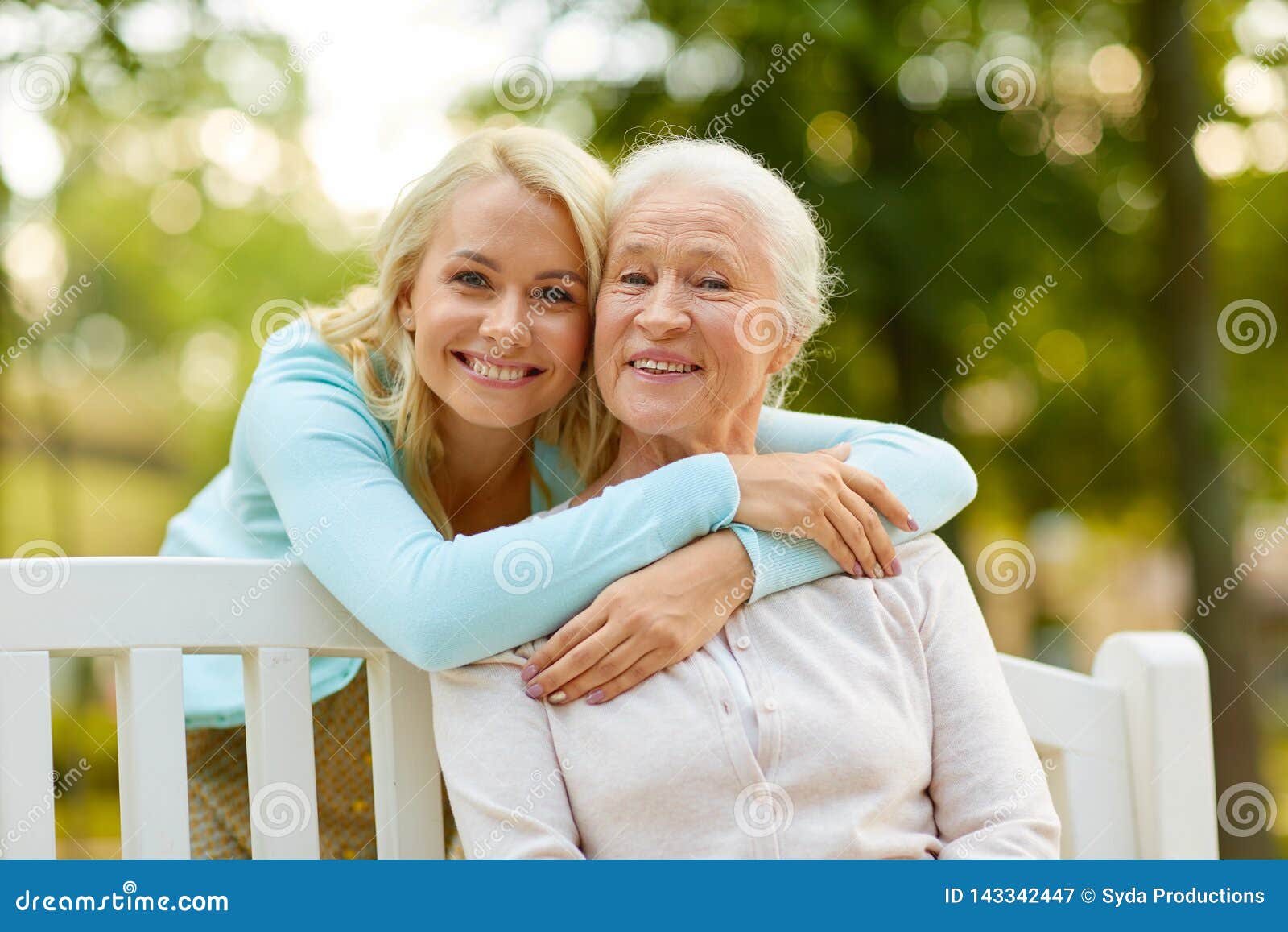 daughter with senior mother hugging on park bench