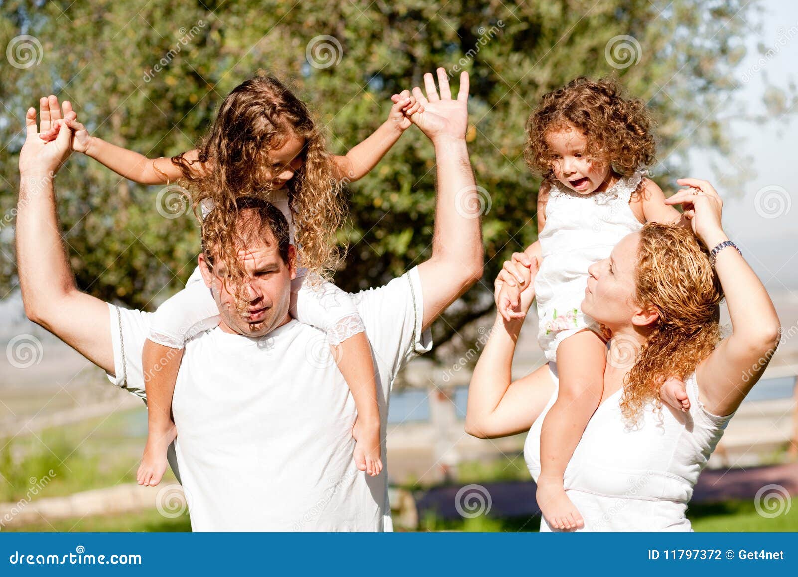 Daughters Enjoying Their Ride on Parents Shoulders Stock Photo Image