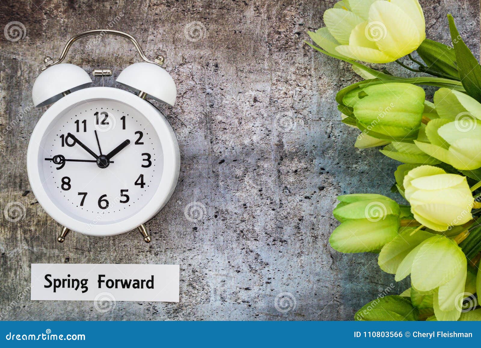 daylight savings time spring forward concept top down view with white clock and green tulips