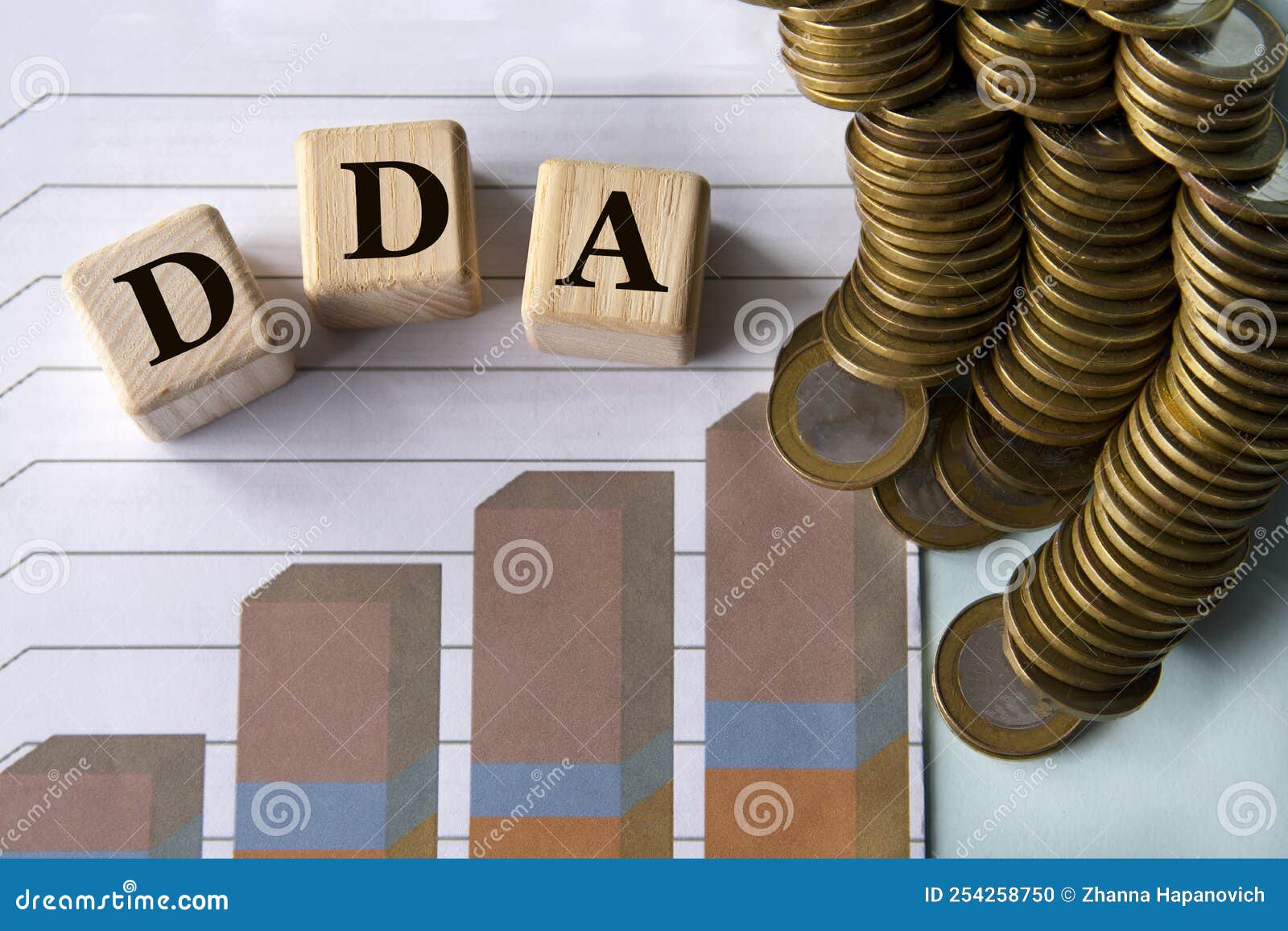 dda - acronym on a green sheet on the background of a graph, pencils and coins