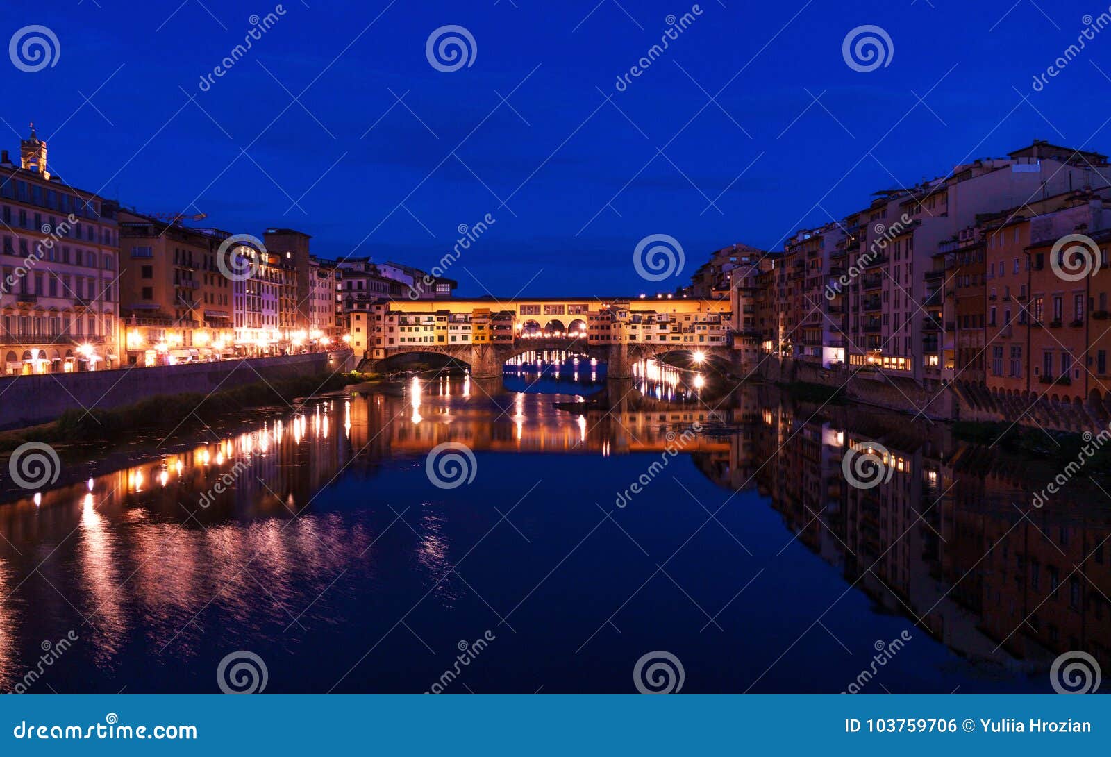 De brug van Pontevecchio in Florence bij nacht met stadslichten die in Arno-rivier nadenken