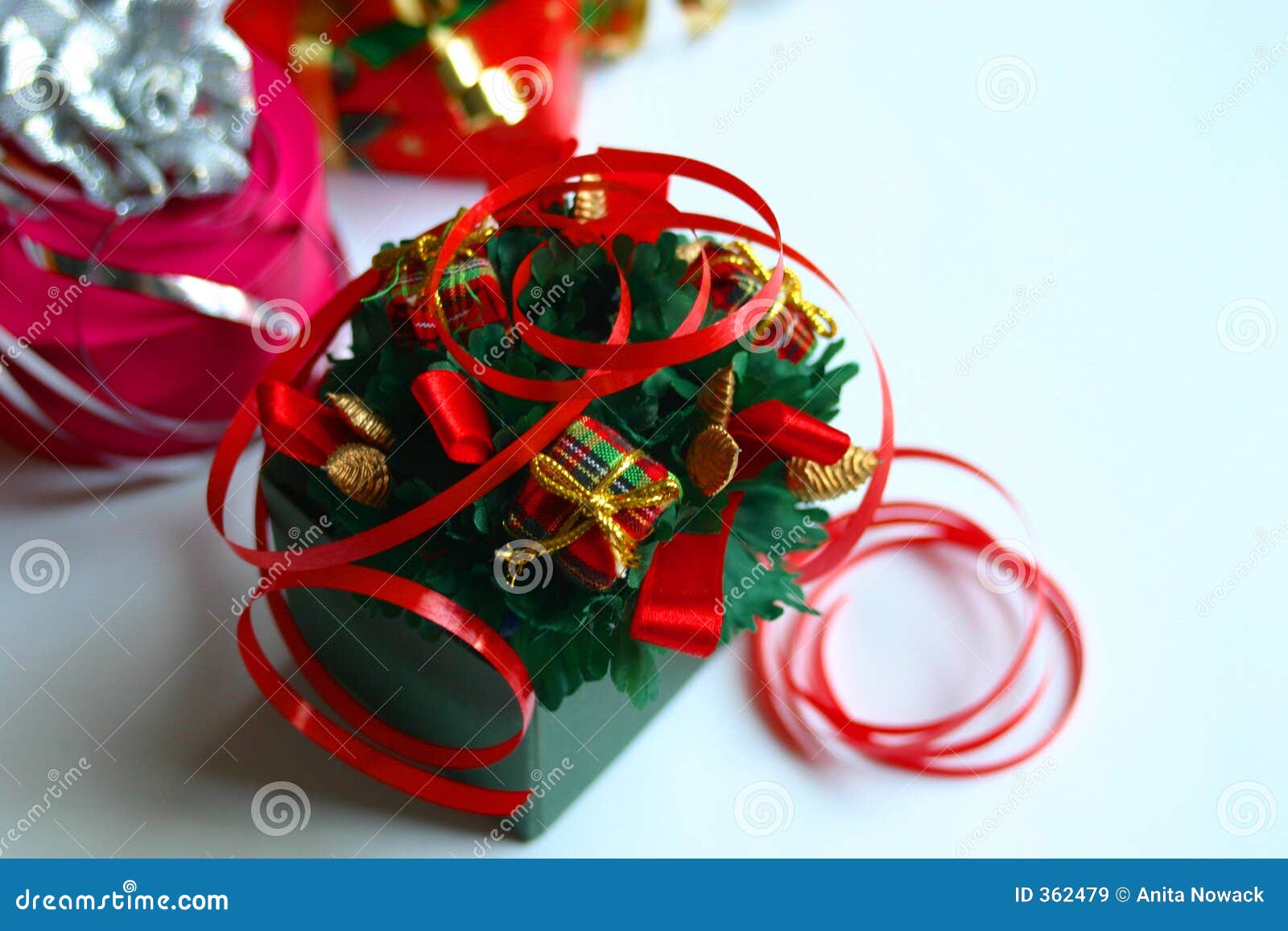 De Giften van Kerstmis. Het dichtere schot van een gift verpakte in groen met rode krullende linten en christmasy trinkets.