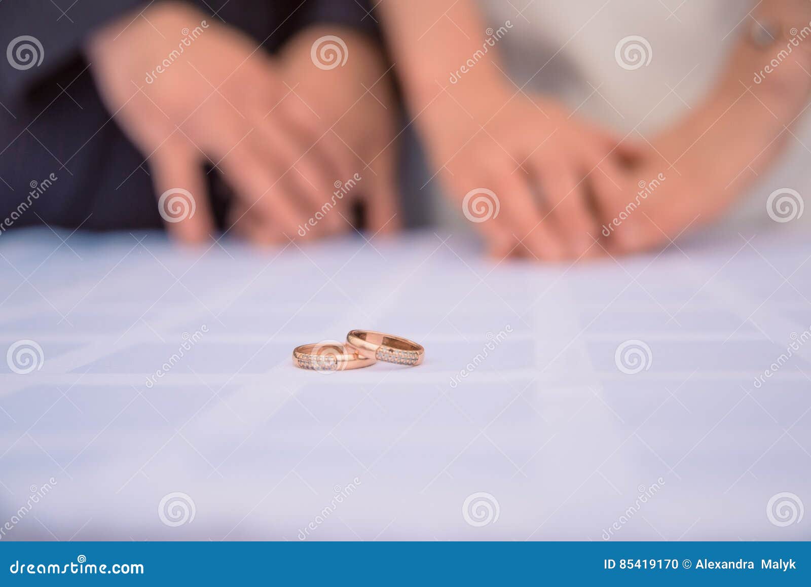 De gouden trouwringen liggen op de lijst achter hen vertroebelden de handen van de jonggehuwden Bruidhand met ring een boeket. Bruidhand met gouden ring een huwelijksboeket op lijst