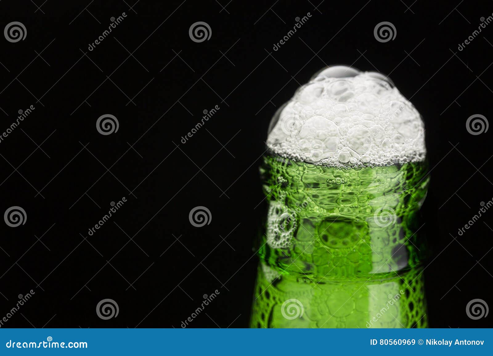 De groene hals van de bierfles met schuim op zwarte achtergrond