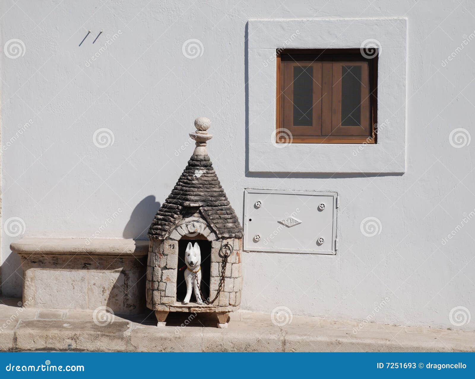 De Hut van de Hond van Trullo. Beweer hondhut buiten een traditionele trullihuizen in Alberobello in Puglia, zuidelijk Italië. Trulli, wat in het kader van de wetten van de Erfenis van de Wereld van Unesco beschermd zijn, is traditionele kalksteenhuizen met overkoepelde of kegeldaken, en is gemeenschappelijk in het gebied Alberobello