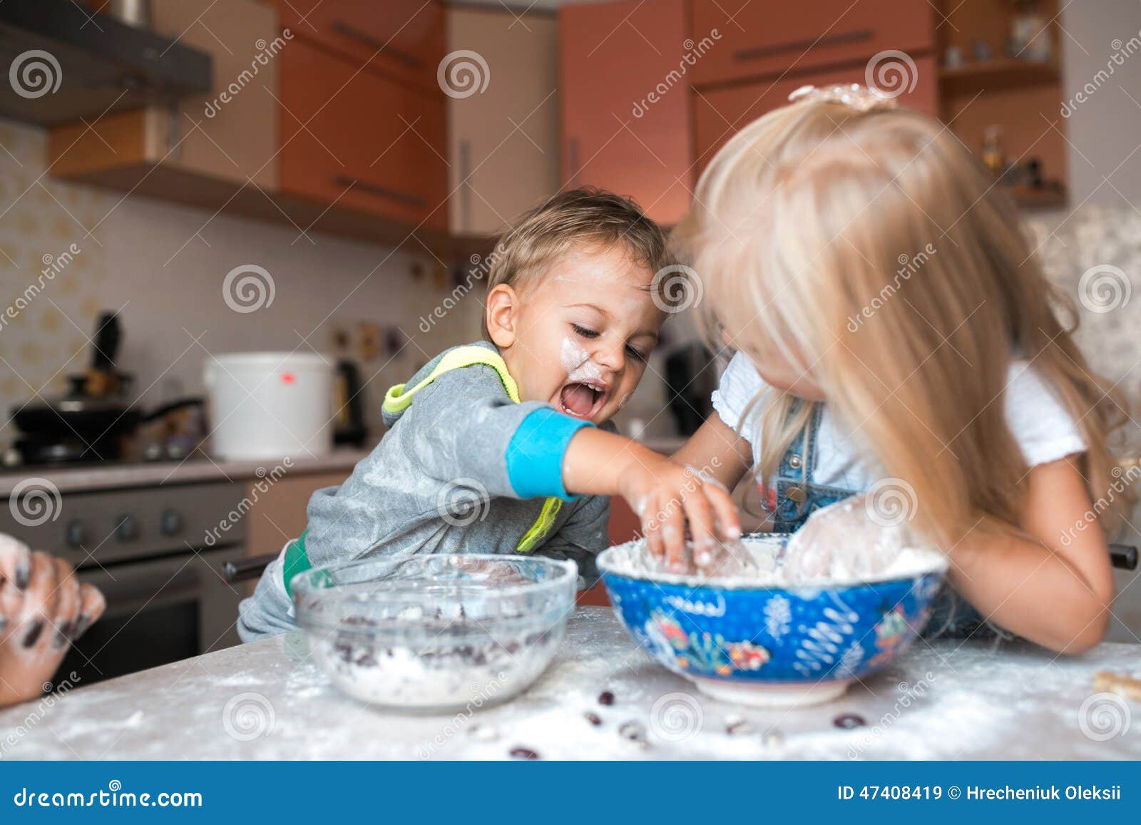 De jonge geitjes op een keuken die een diner koken en hebben pret. Werkelijk aardig paar van weggegaane kinderen die een werk op een keuken doen