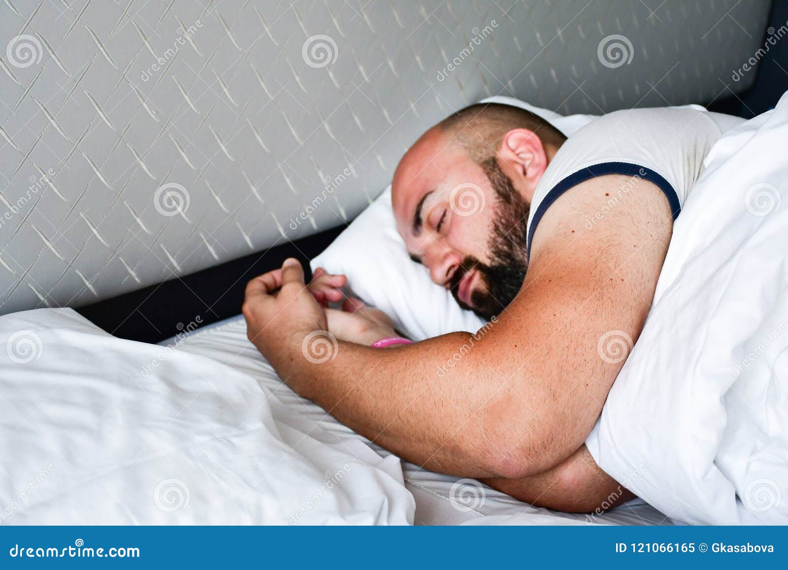 De mens van de slaap. Mooie gelooide gebaarde spiermensenslaap in bed