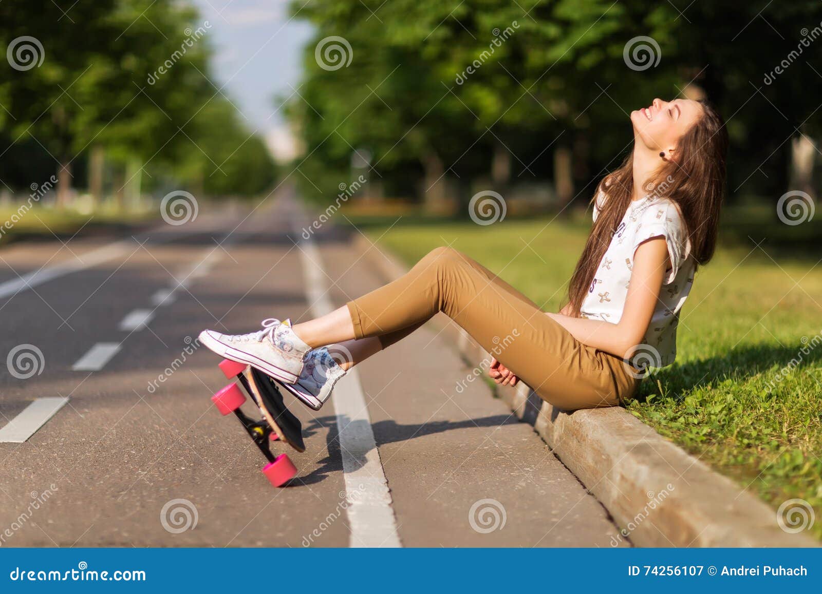 De mooie jonge t-shirt en de broek van meisjes hipster tennisschoenen zetten op tennisschoenen en longboard gelukkig skateboarding In openlucht, levensstijl