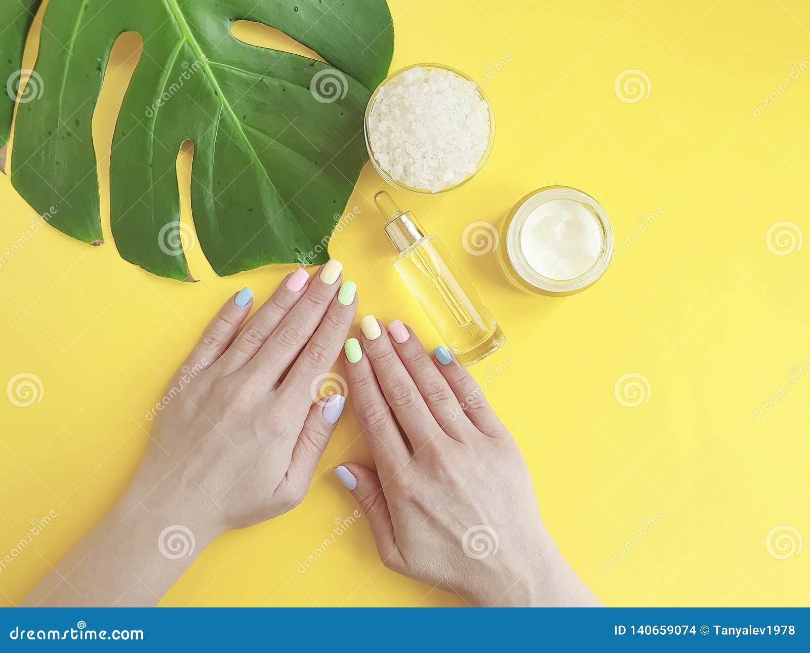 De vrouwelijke creatieve, kosmetische room van de handenmanicure, monsterablad, op een gele achtergrond. Vrouwelijke handenmanicure, het kosmetische blad van roommonstera, op een gele creatieve achtergrond