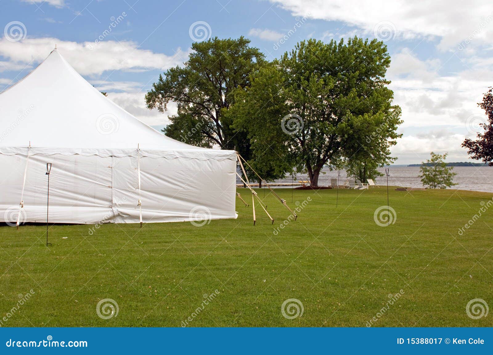 De witte tent van de huwelijkspartij. Een grote witte tent van de huwelijkspartij op een grasrijk gazon bij een oever van het meertoevlucht.