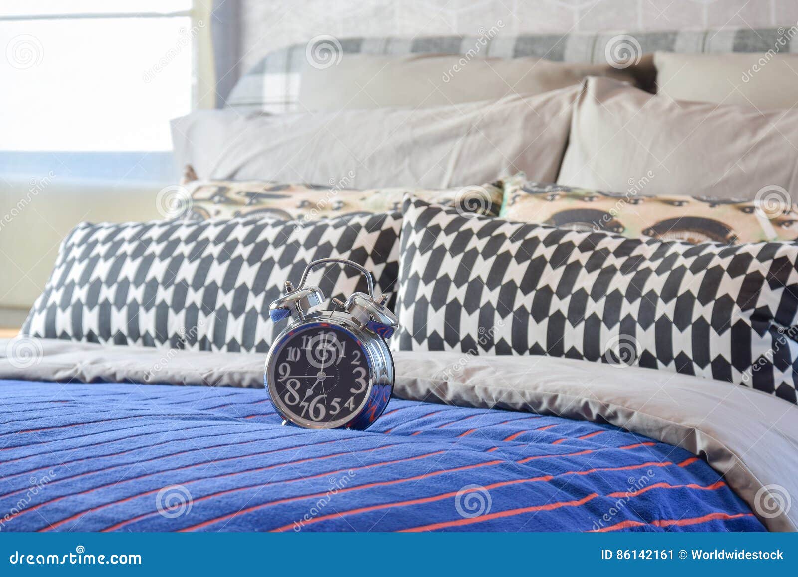 Decorative Alarm Clock with Black and White Pillows on Bed Stock Image