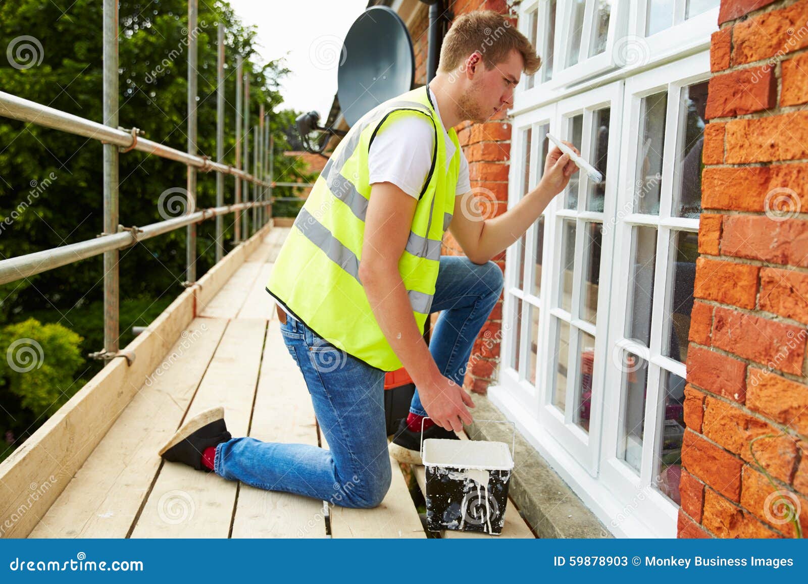 decorator on scaffolding painting exterior house windows