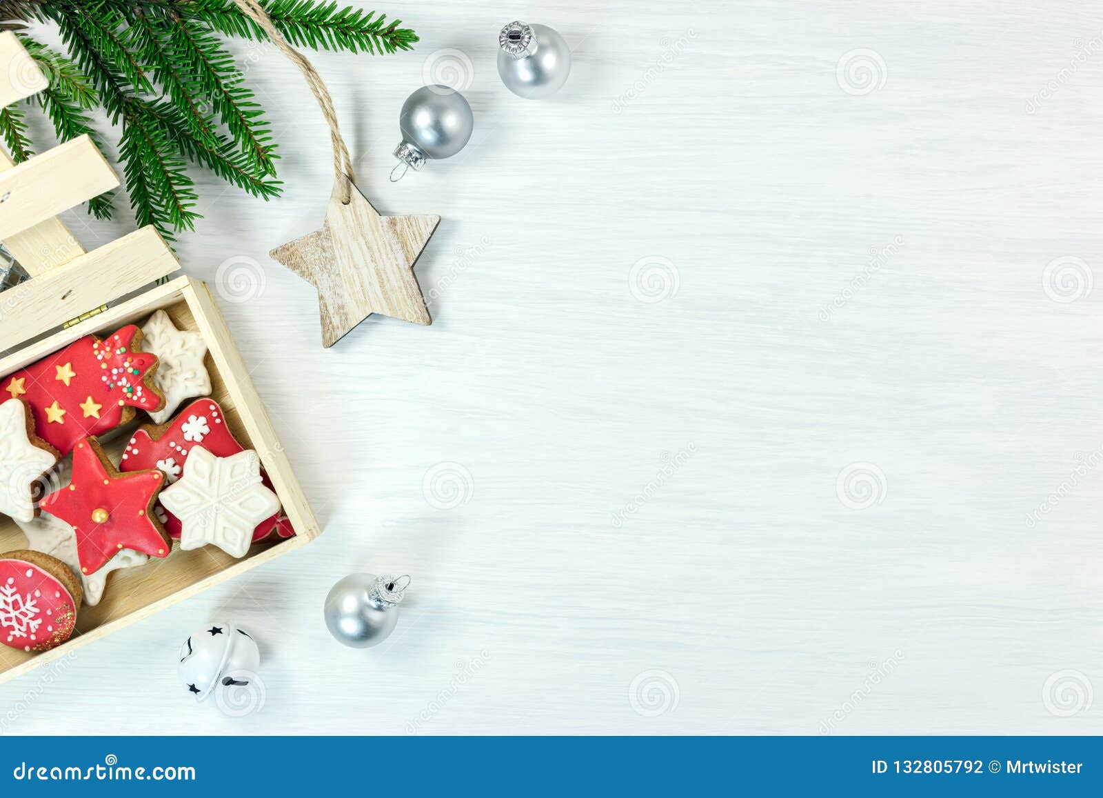 Decorações do Natal com as cookies feitos a mão do pão-de-espécie na caixa. O ornamento do Natal no fundo de madeira branco liso coloca decorações dos feriados de inverno com as cookies feitos a mão do pão-de-espécie na caixa, no ramo de árvore do abeto e nas bolas de prata de vidro