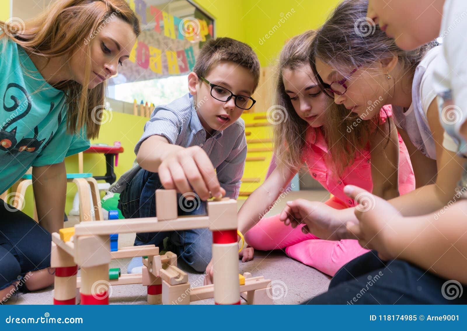 dedicated kindergarten teacher helping children with the construction of a train