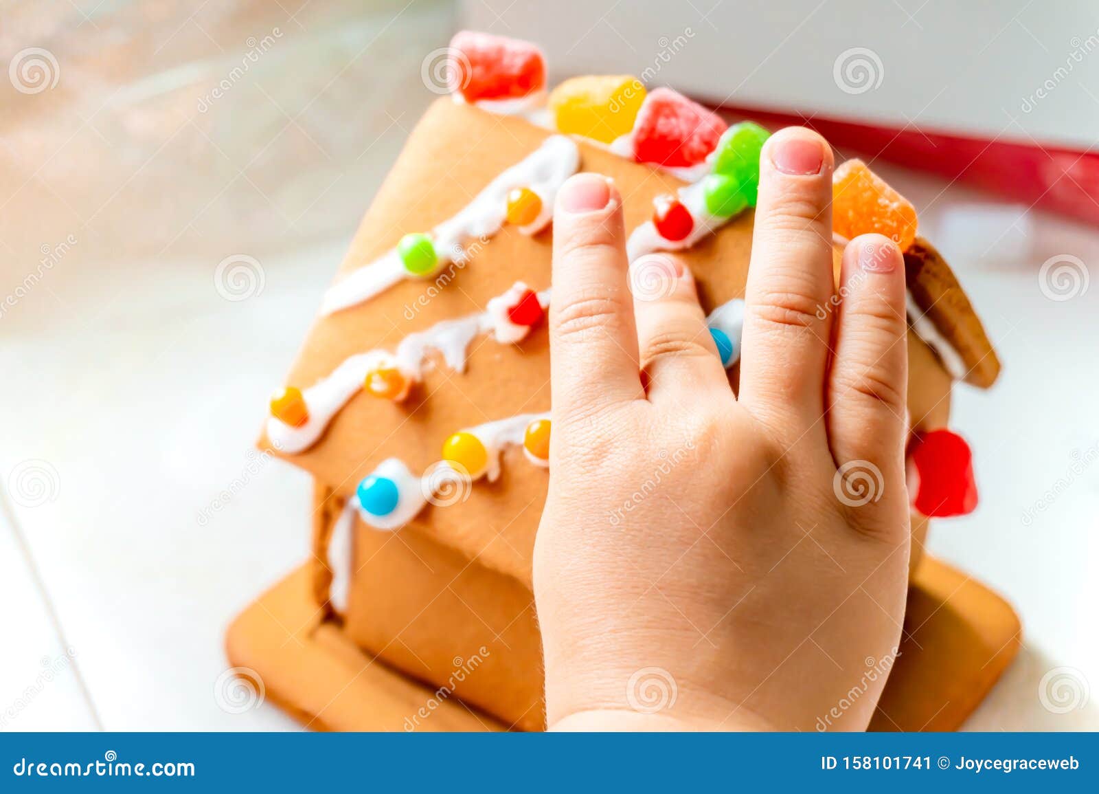 Dedos Para Niños Colocando Pelotas De Caramelo Y Muñecas En El Techo De Una Casa De Jengibre Con Azúcar De Glaseado Como Una Cr Imagen de archivo - Imagen de muñecas, niños: