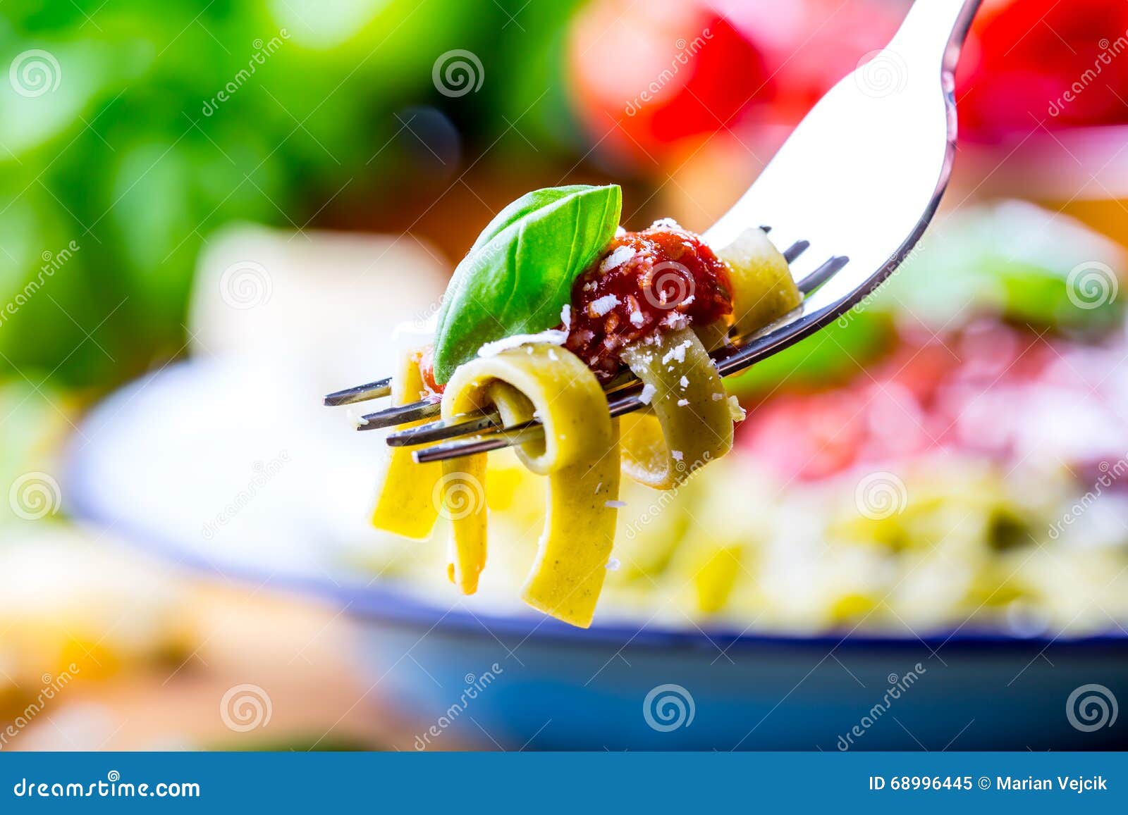 Deegwaren Italiaanse en Mediterrane keuken Deegwaren Fettuccine met de bladerenknoflook van het tomatensausbasilicum en parmezaanse kaaskaas Een oude huiskeuken met oud keukengerei Gedeelte van op vorkdeegwaren met tomatensaus en basilicumbladeren