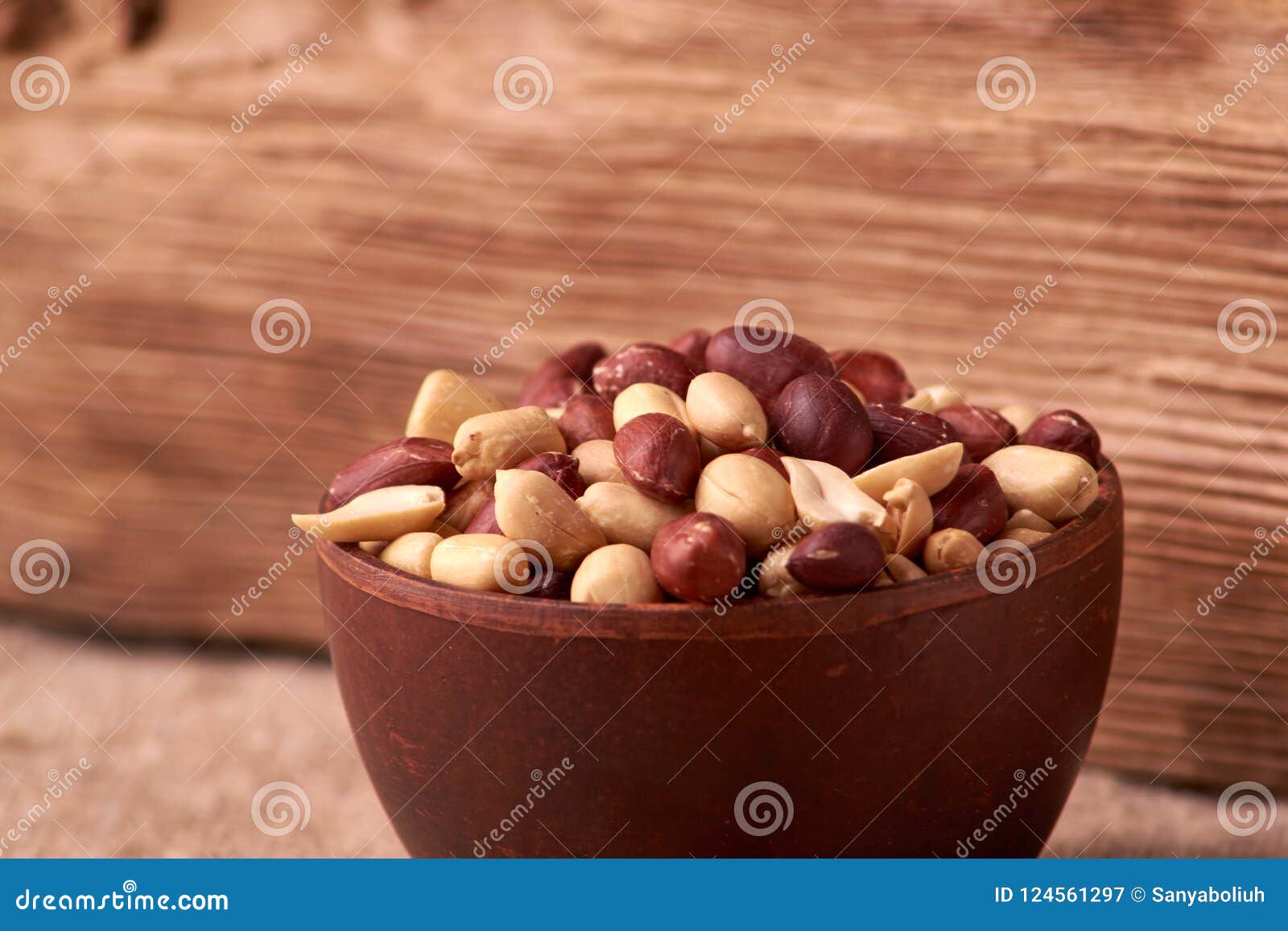 deep fried peanuts in clay bowl over rustic wicker background. selective focus