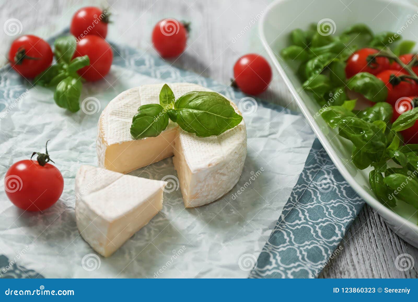 Delicious Brie Cheese with Basil and Cherry Tomatoes on Table Stock