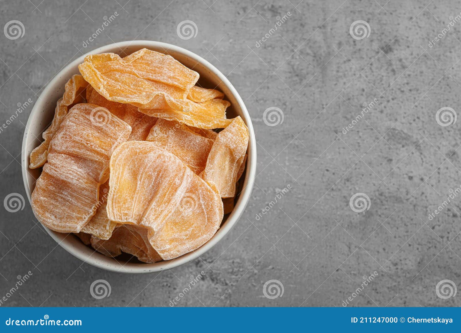 Delicious Dried Jackfruit Slices in Bowl on Grey Table, Top View. Space for Text Stock Photo