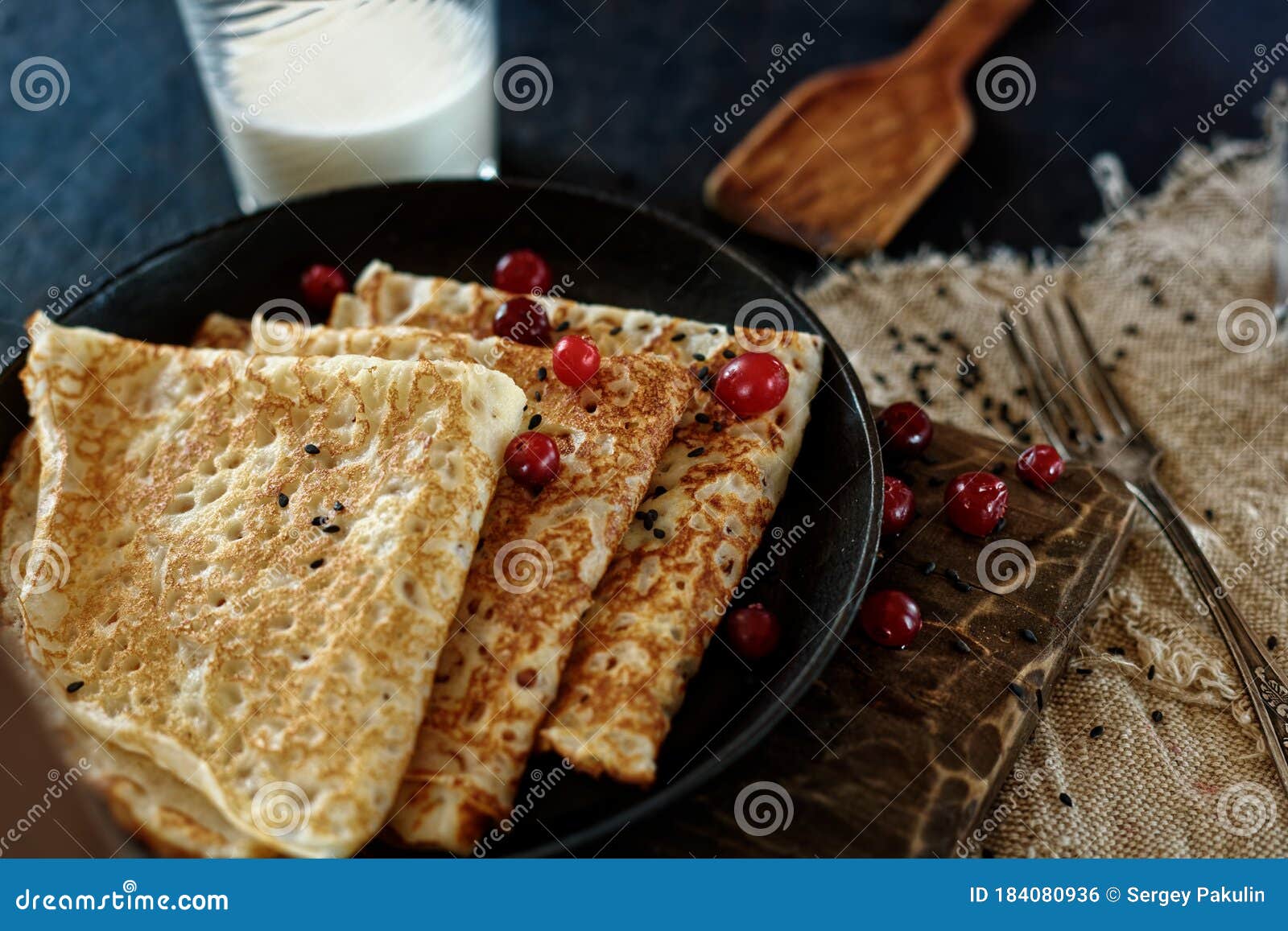 delicious home-cooked food. pancakes in a frying pan with cranberry berries and milk. rustic style