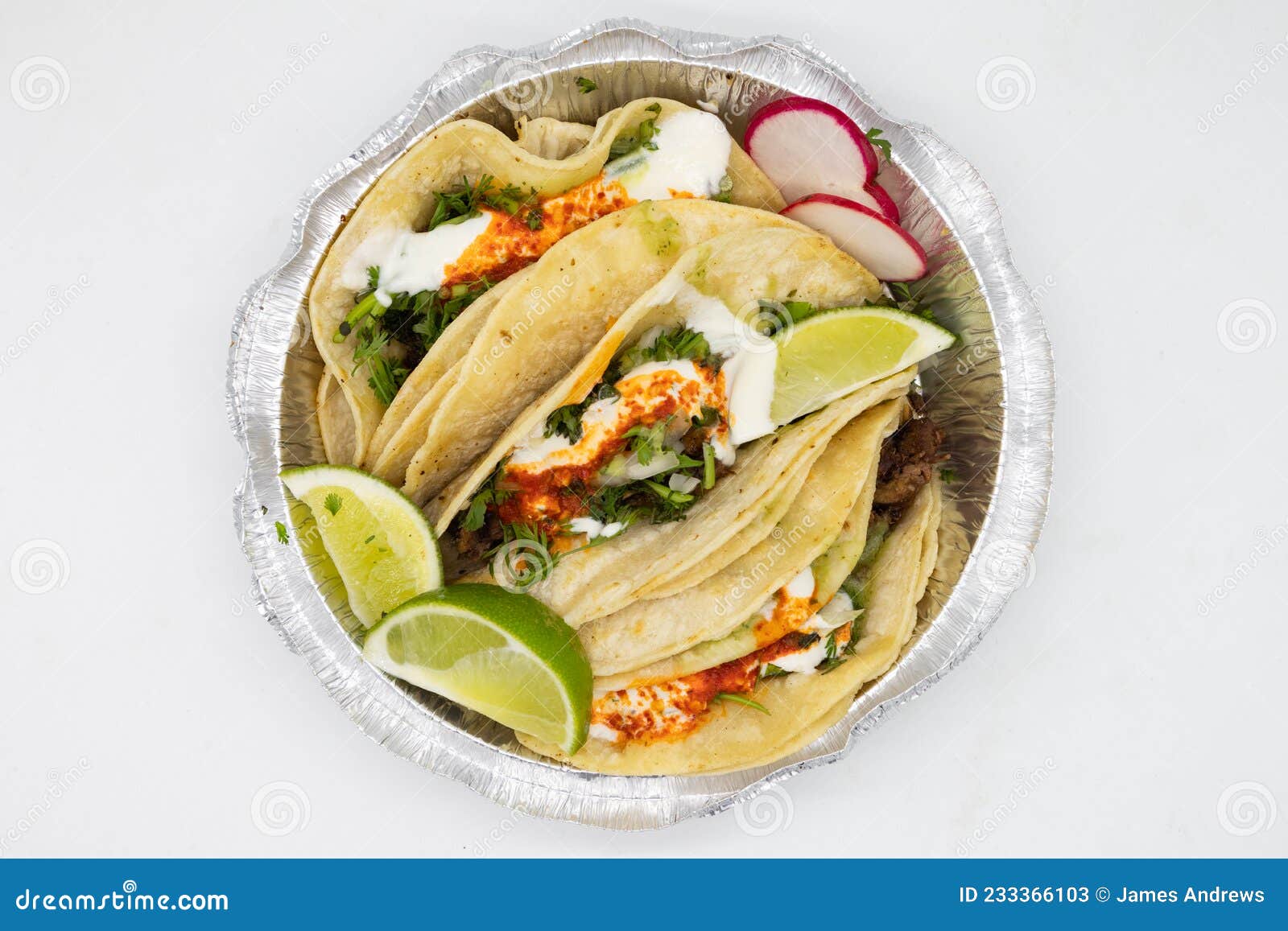 delicious lengua tacos with limes and sour cream in a takeout container