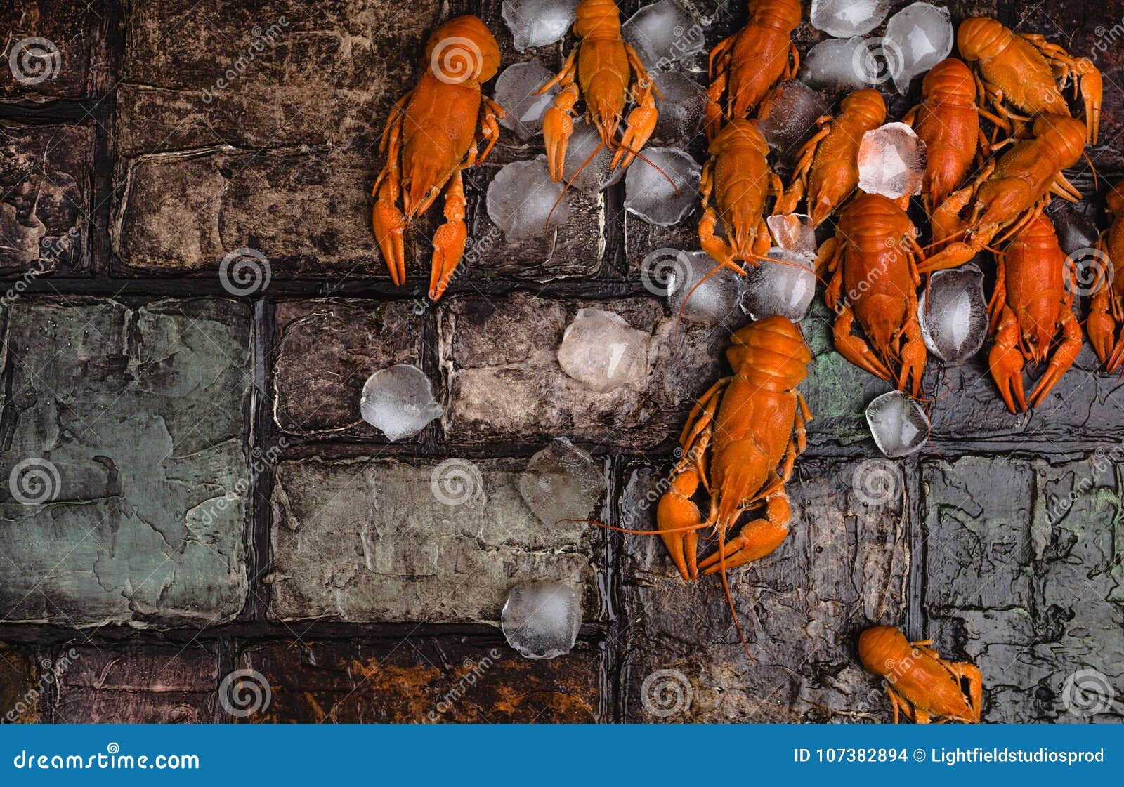 Delicious Lobsters with Ice Cubes on Brick Wall Surface Stock Photo