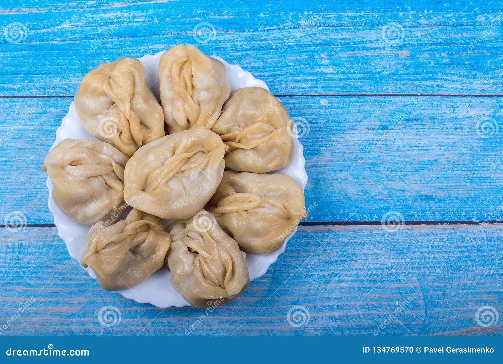 Delicious mantas on a white plate on blue wooden background, Asian cuisine, traditional national dish.