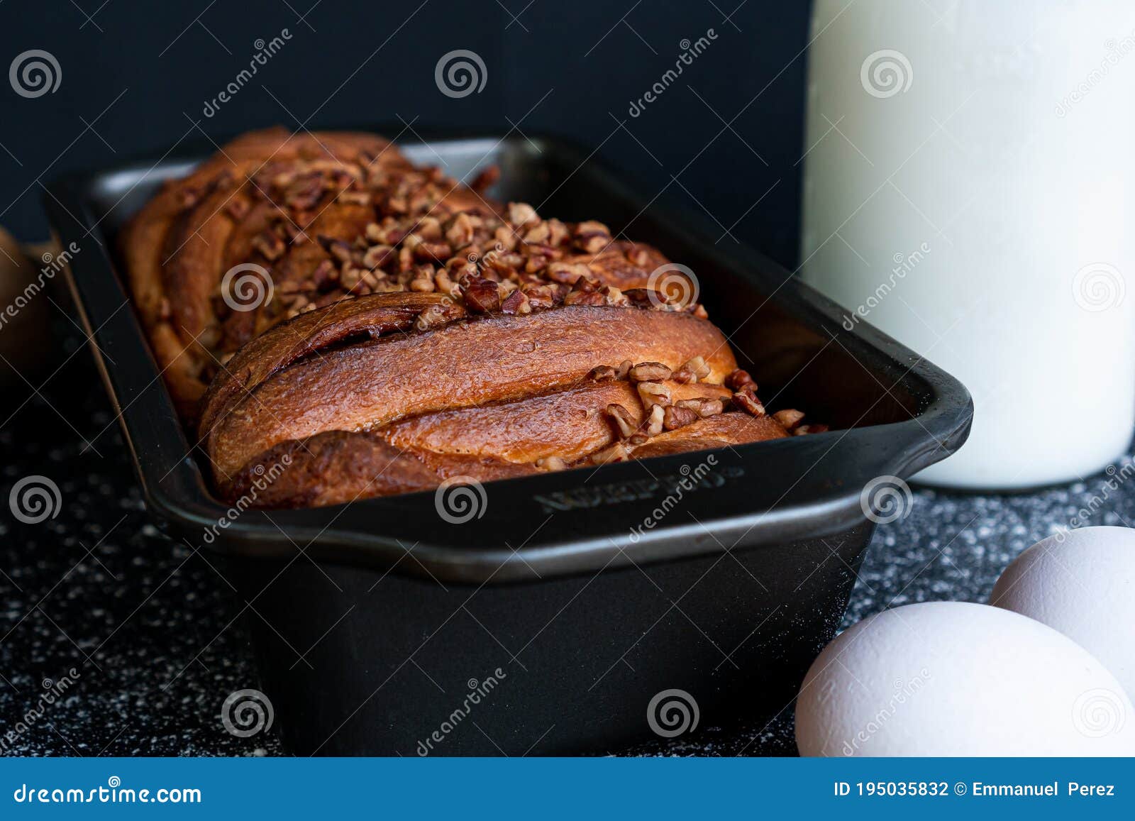 delicious trenza bread garnished with ground nuts with a bottle of milk, eggs in front and a black background