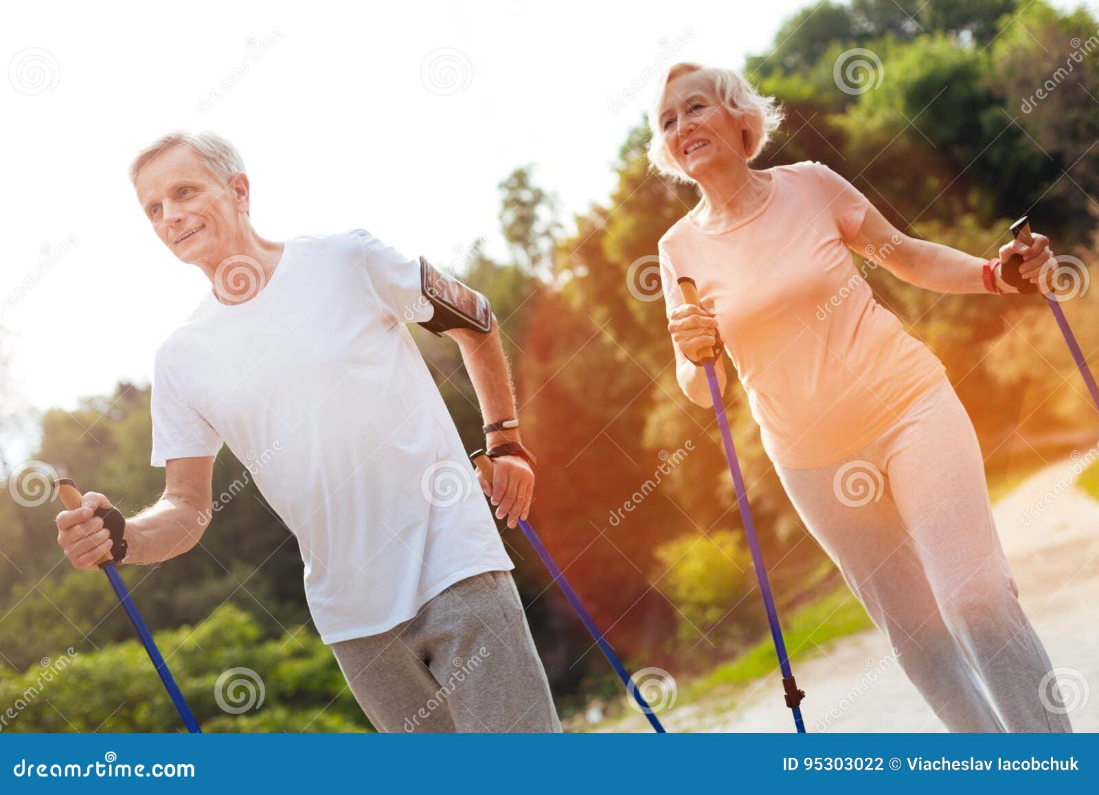 delighted elderly couple practicing nordic walking