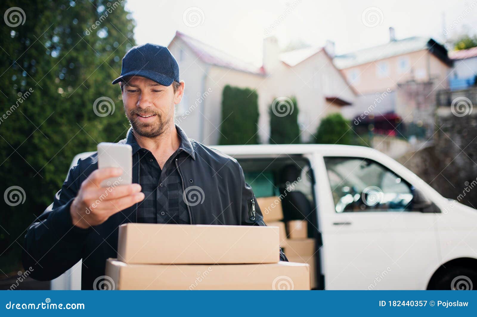 Delivery Man Courier Delivering Parcel Box in Town Using Smartphone