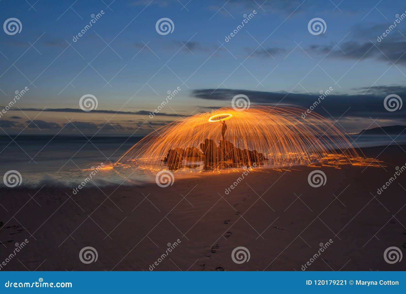 Den härliga Lightpainted orben med flyg gristrar på en strand med en varm solnedgång i bakgrunden