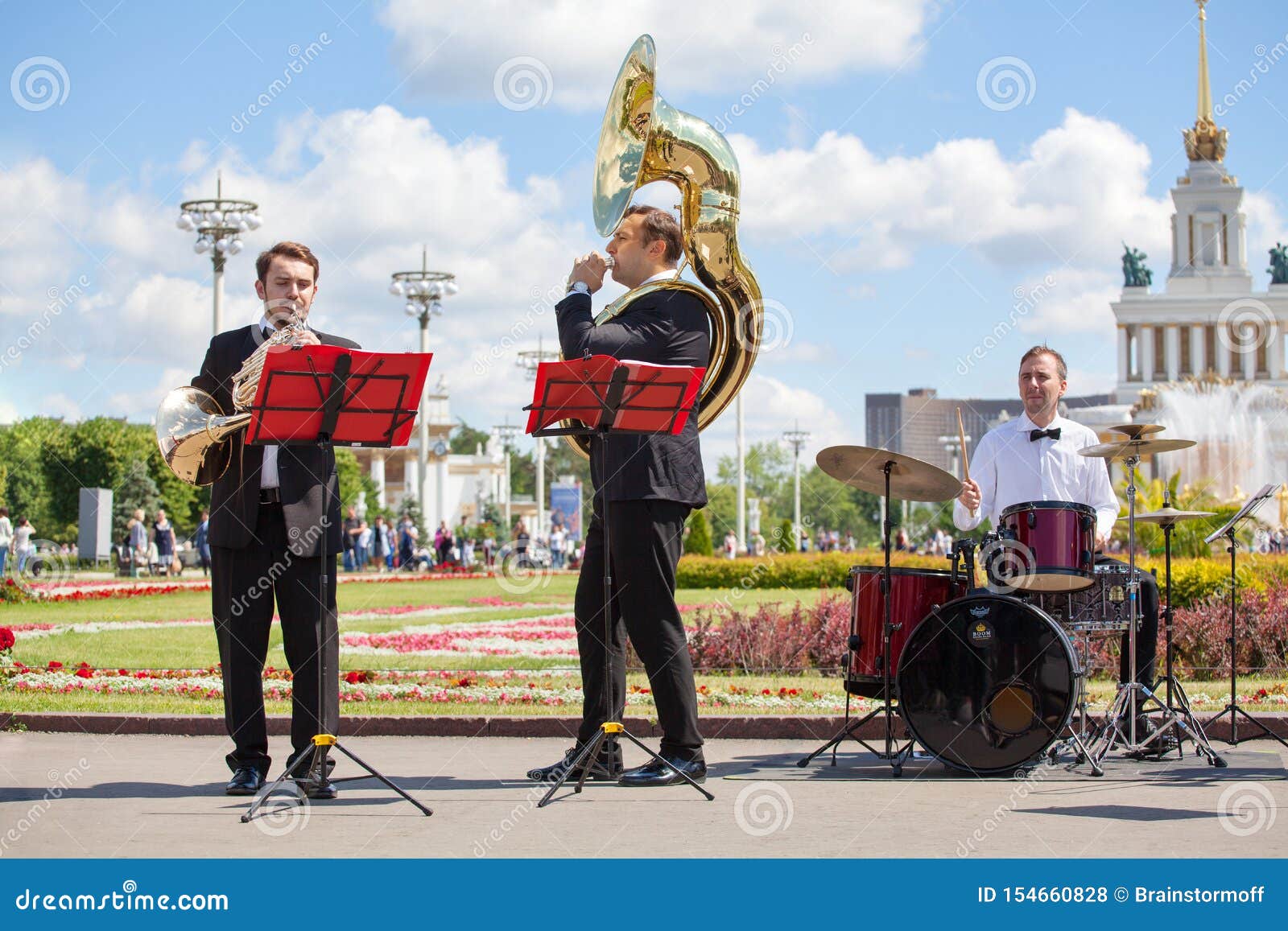 Den nya livmässingsmusikbandet, orkester utför musik, vind, och slagverkmusikinstrumentspelare, musiker spelar trumpeter. Moskva Ryssland - Juni 16, 2019: Den nya livmässingsmusikbandet, orkester utför musik, vind och slagverkmusikinstrumentspelare, spelar musiker trumpeter, det franska hornet, sousaphone, och drumm i VDNKh parkerar