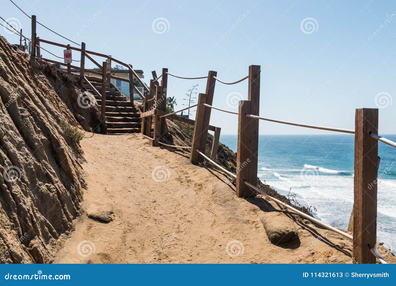 Den smutsslingan och trappan på klippan på fyr` s sätter på land. En smutsslinga och trappan på sidan av en klippa på fyr` s sätter på land i Encinitas, Kalifornien