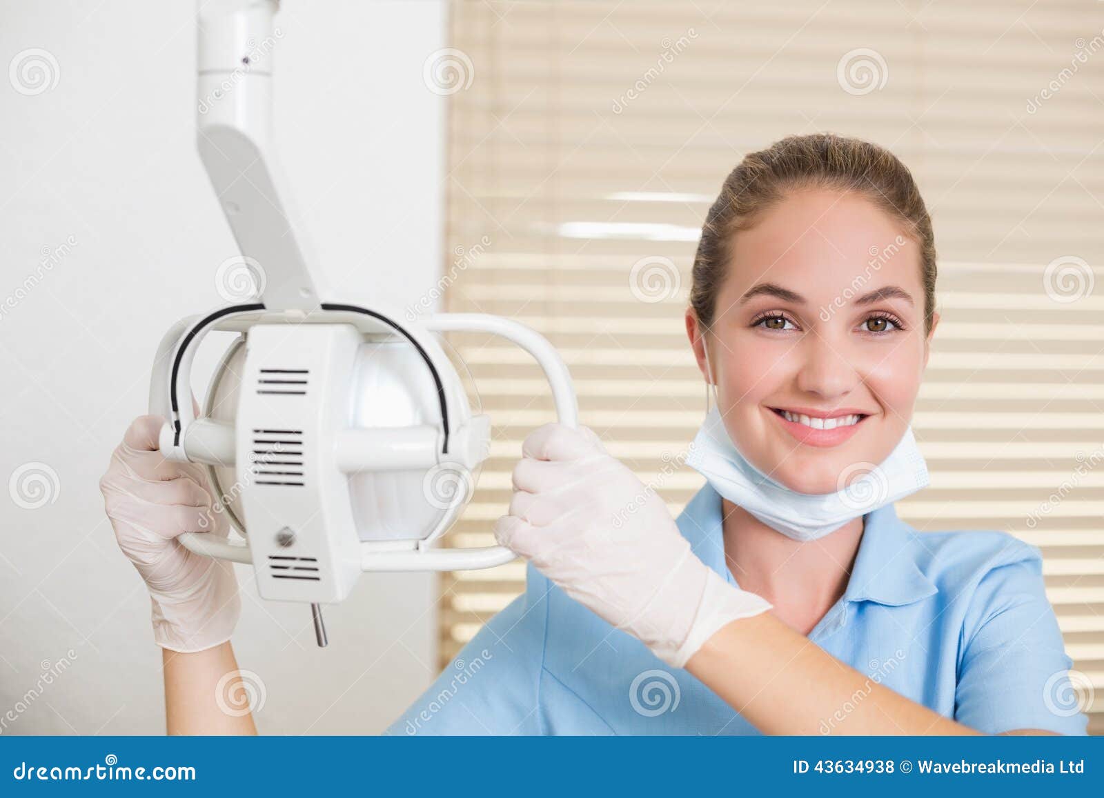 dental assistant smiling at camera beside light