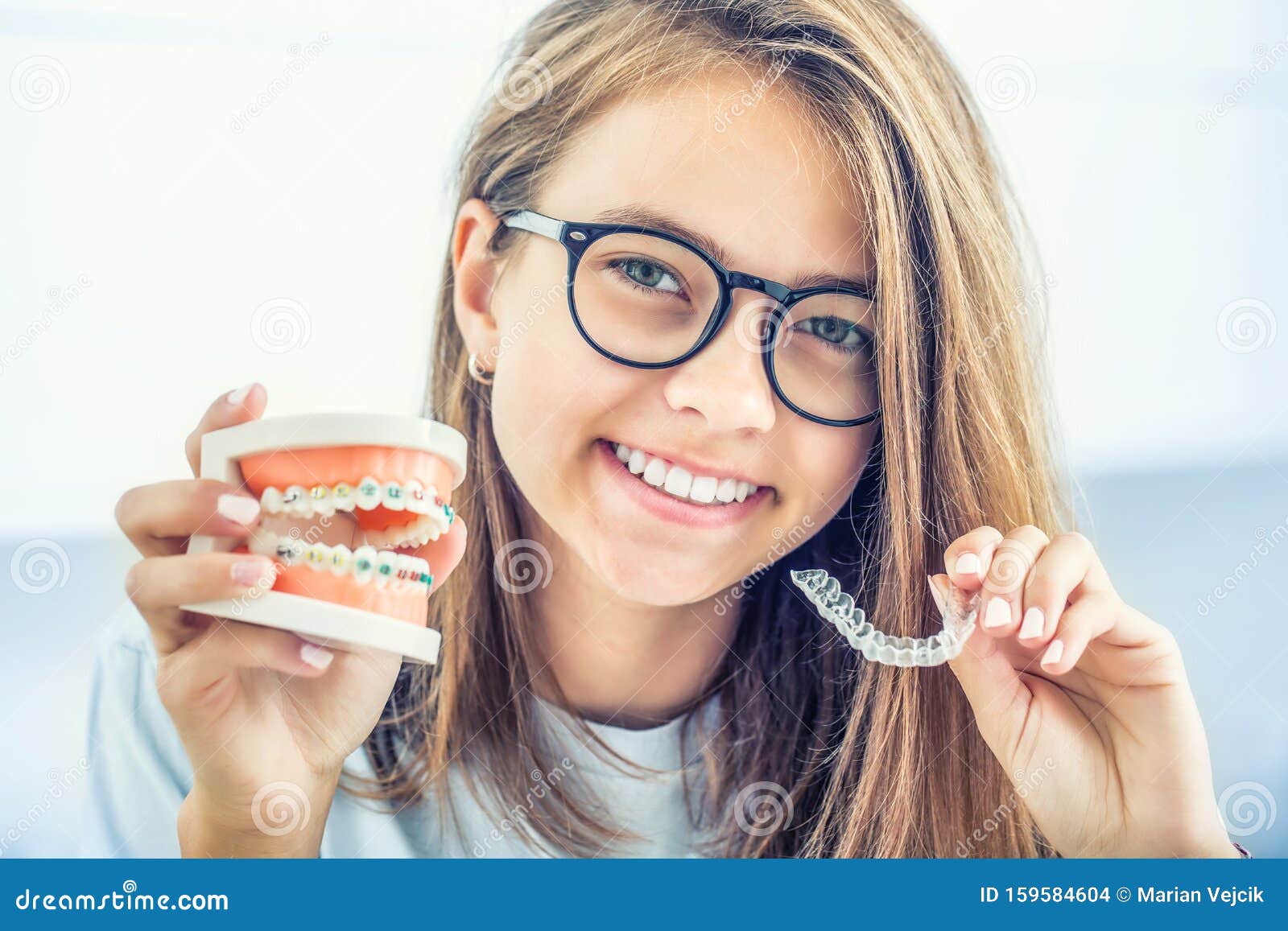 dental invisible braces or silicone trainer in the hands of a young smiling girl. orthodontic concept - invisalign