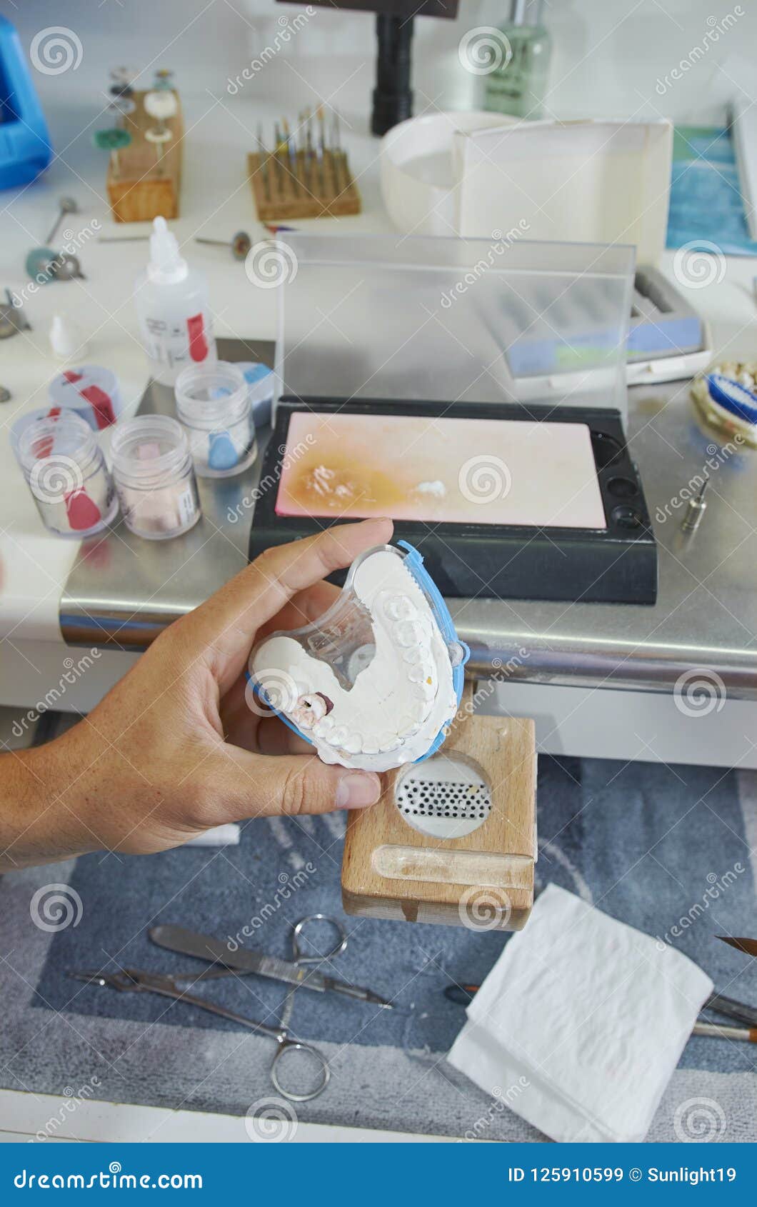 Dental Technician Using a Brush with Ceramic Dental Implants in Stock