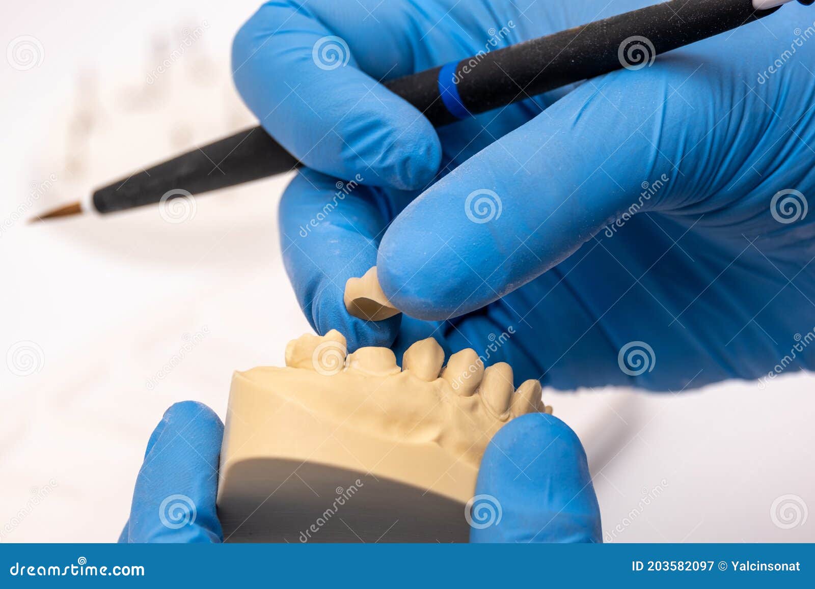 Dental Technician Using a Brush with Ceramic Dental Implants in His
