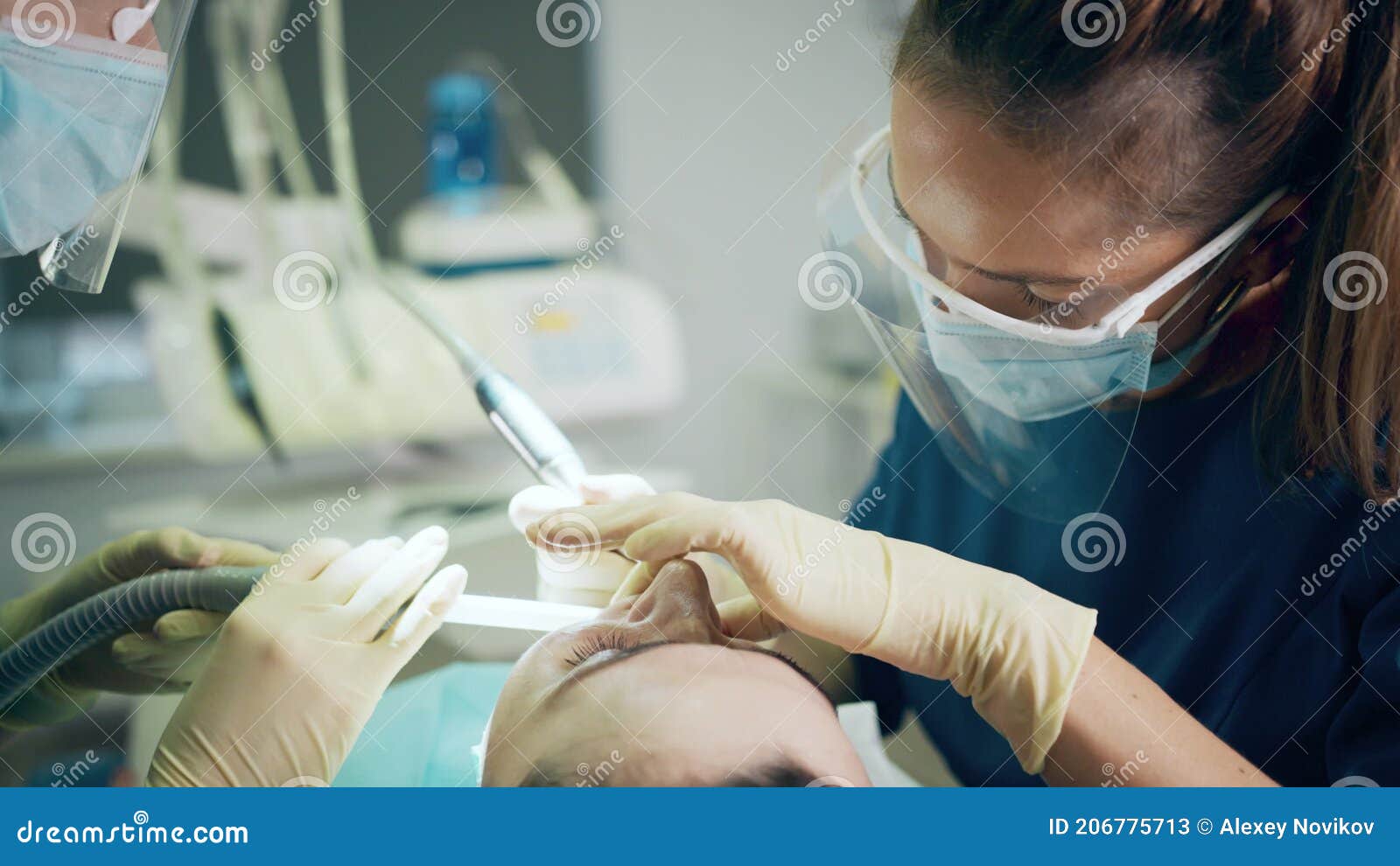Dentist and Assistant Wearing Protective Face Shields at Work with a