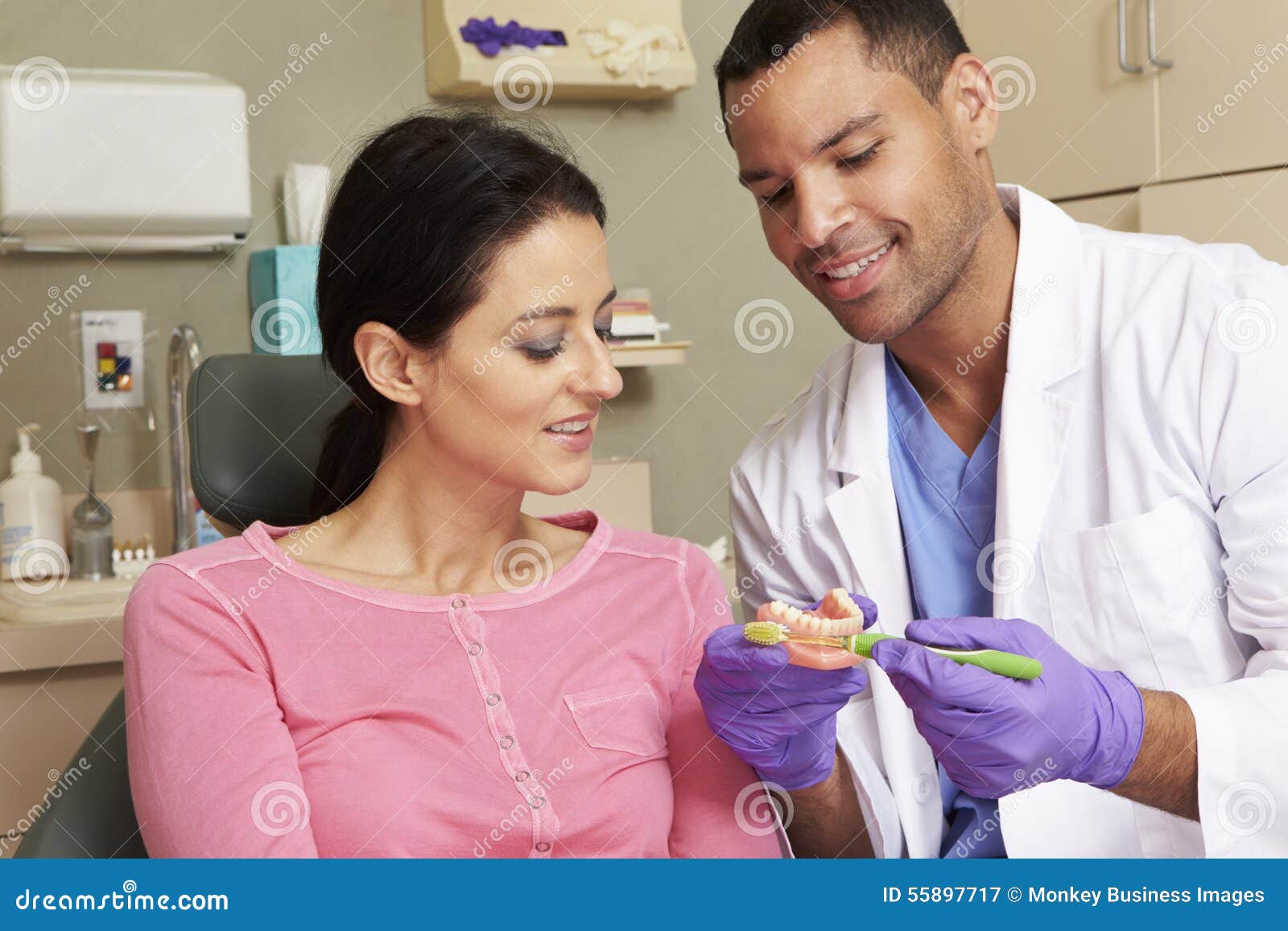 dentist demonstrating how to brush teeth to female patient