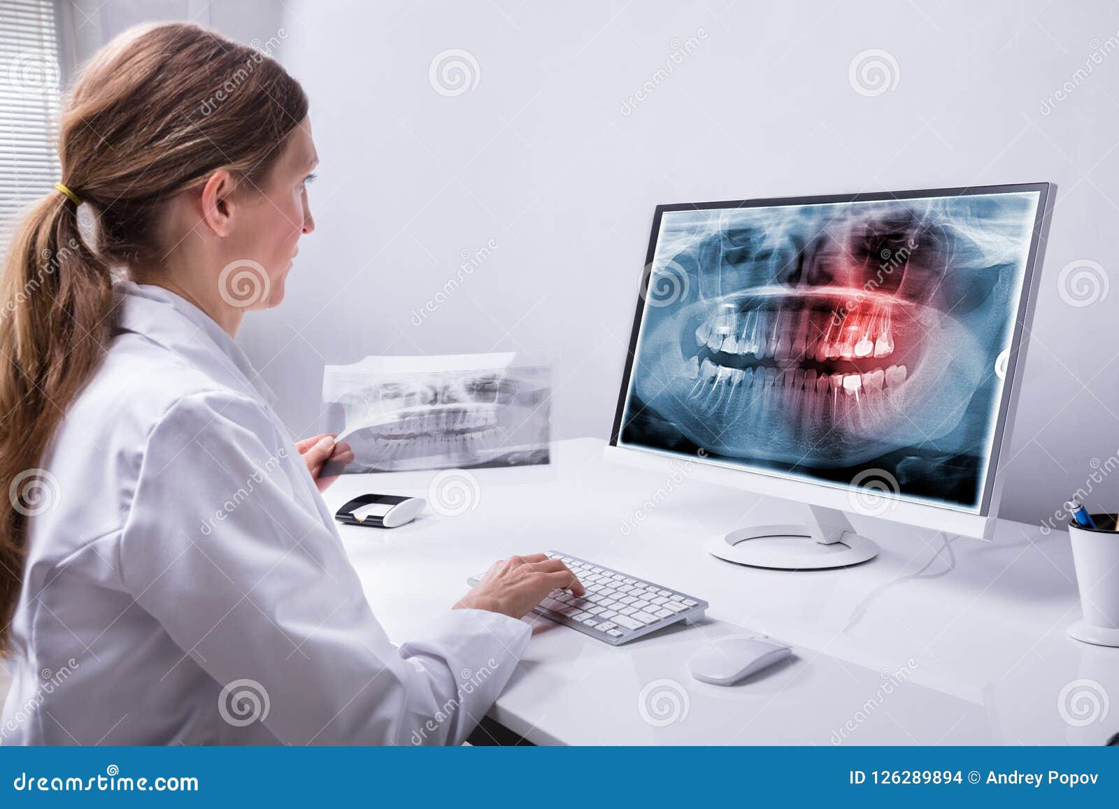 dentist looking at teeth x-ray on computer