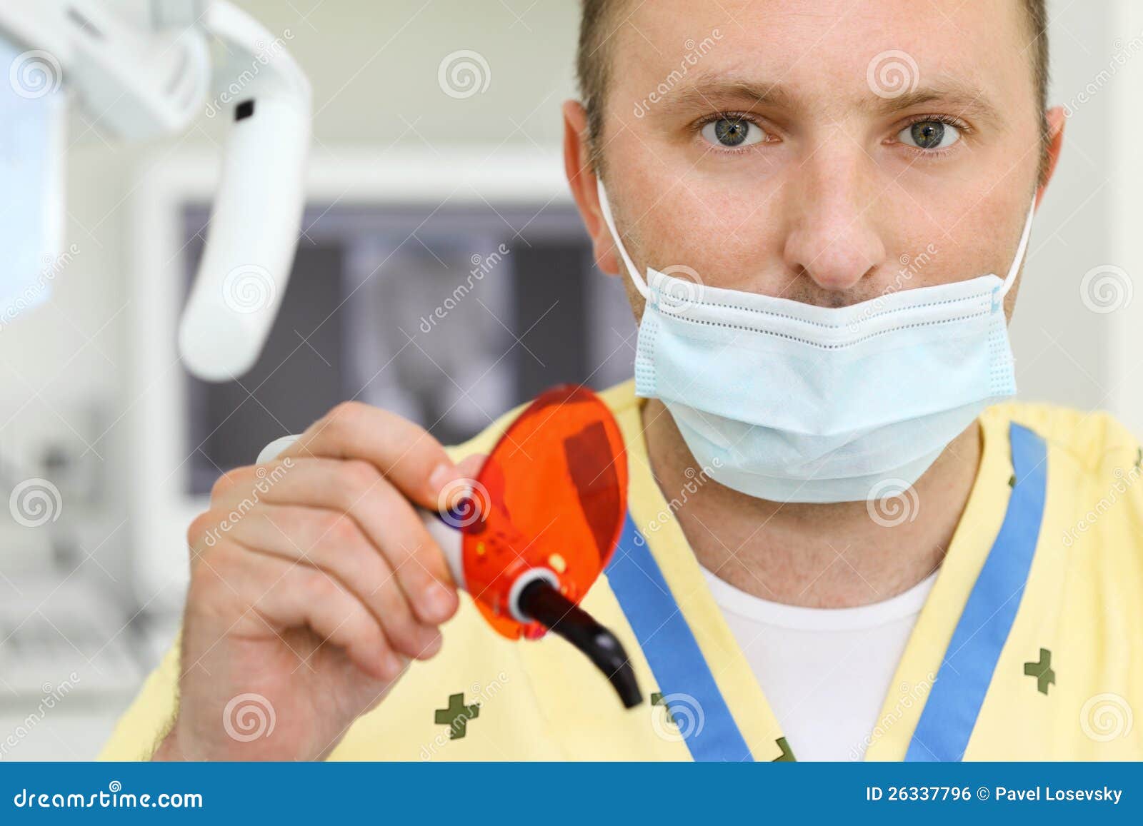 dentist in mask with ultraviolet curing light tool